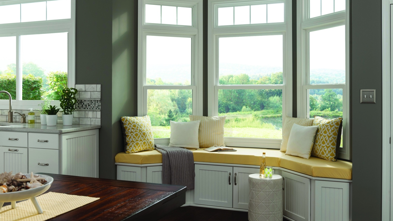 Уютная светлая кухня с эркером в загородном доме в зеленых тонах