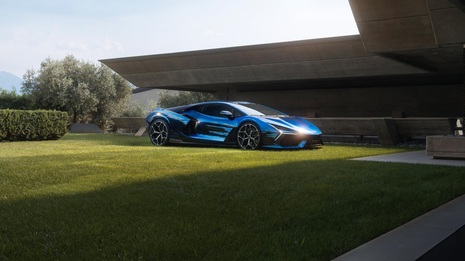 Синий Lamborghini Revuelto Opera Unica 2024 года на зеленой траве