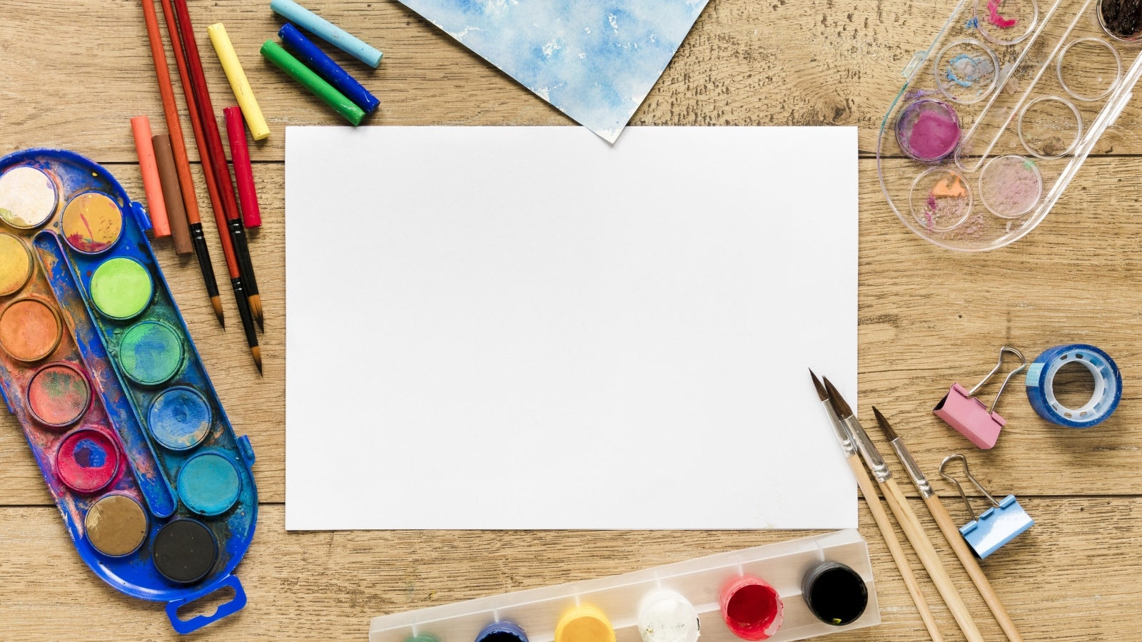 Предметы для рисования с листом бумаги на столе