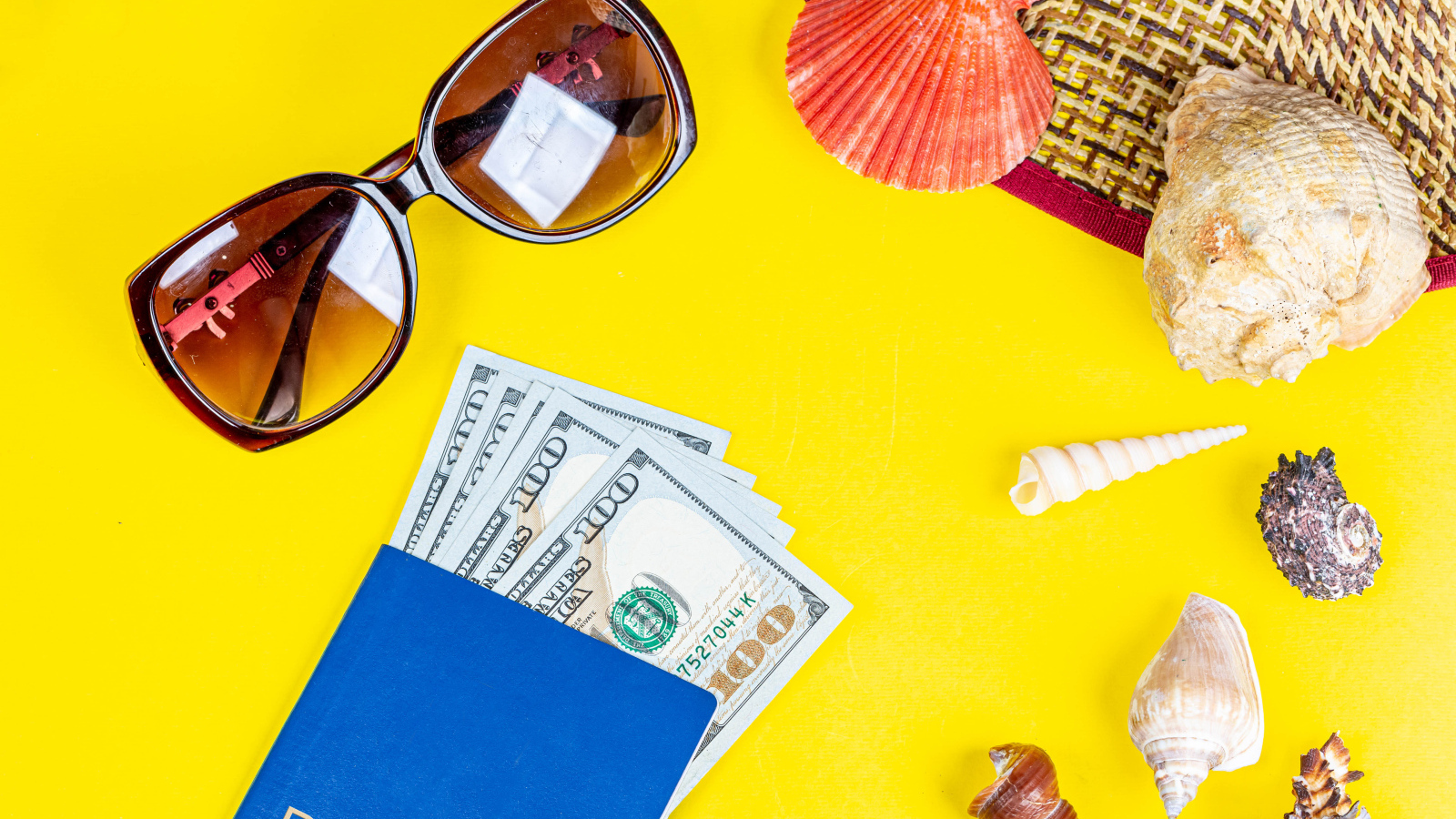 Очки, доллары с паспортом и ракушки на желтом фоне