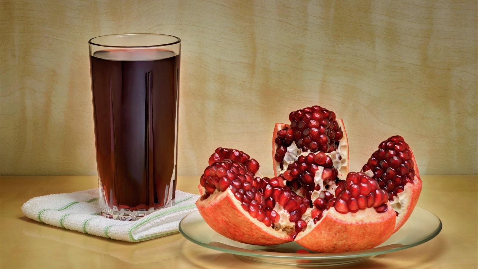 Красный гранат на столе со стаканом сока