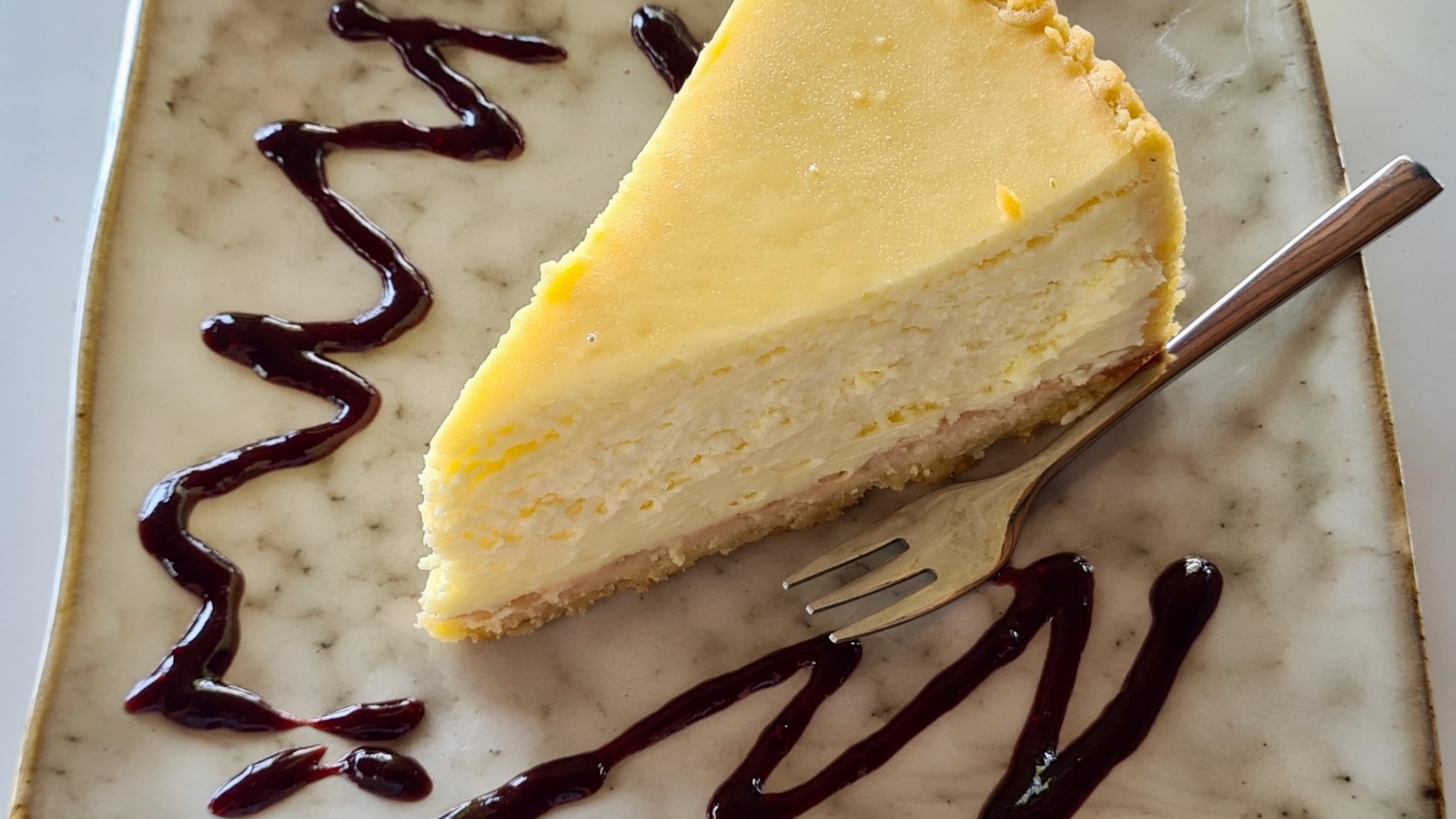 Кусок чизкейка с шоколадным топпингом на тарелке