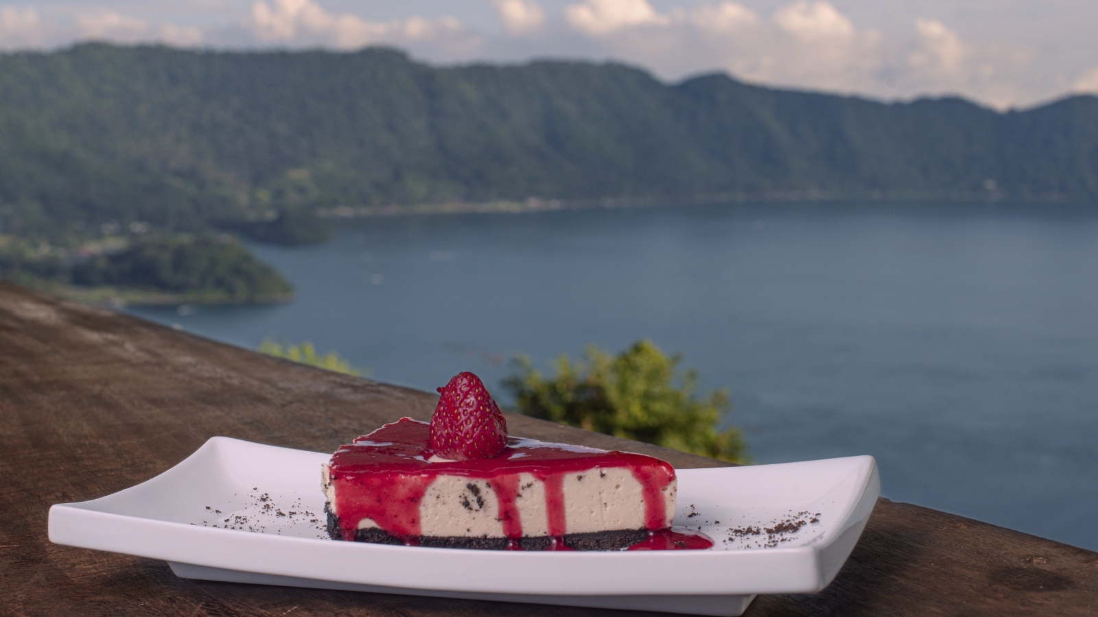 Кусок чизкейка с клубничным джемом на фоне моря