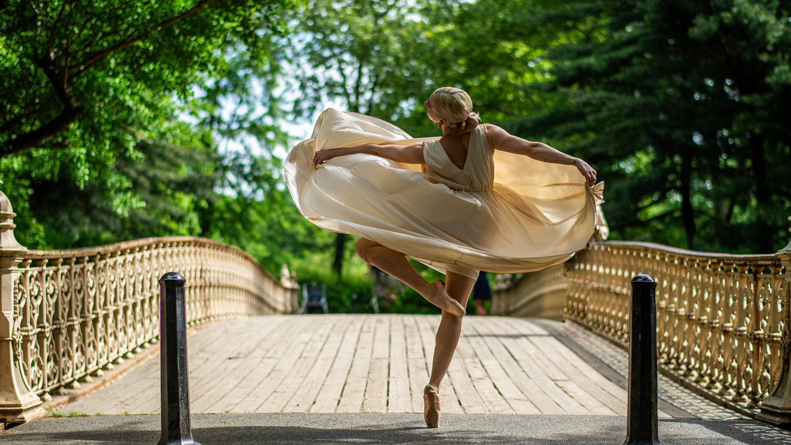 Девушка балерина в стойке на мосту