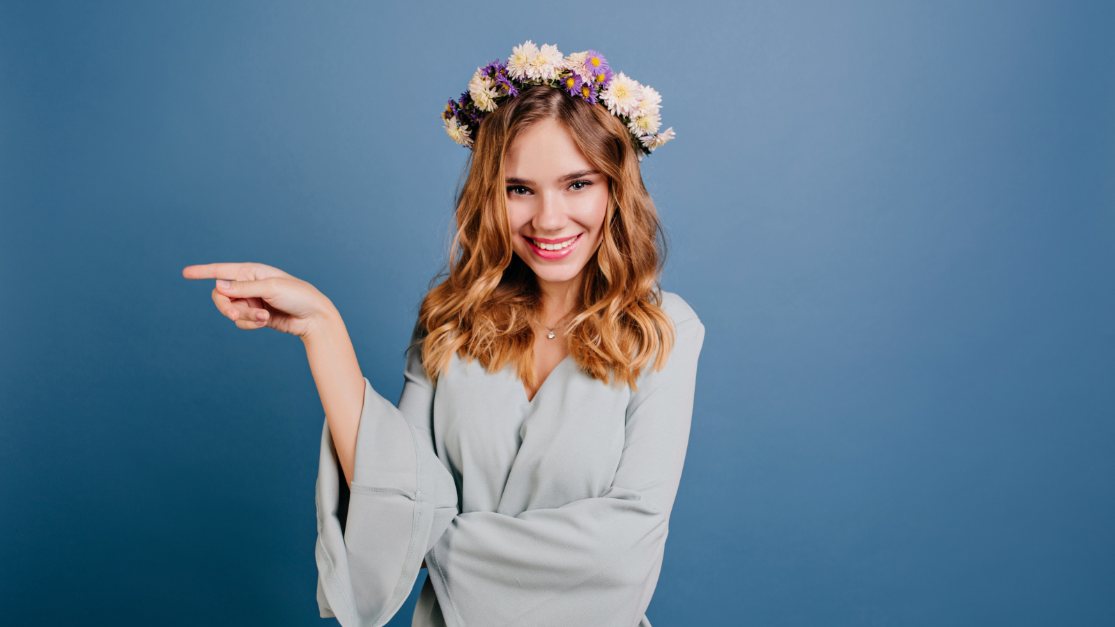 Милая улыбающаяся девушка с венком на голове на сером фоне