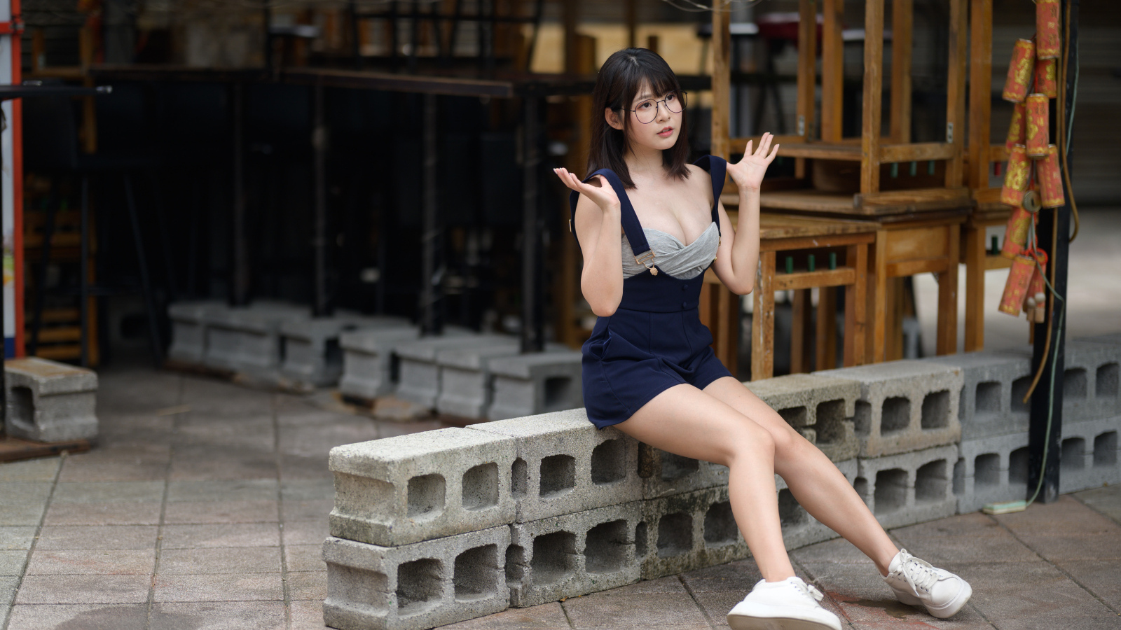 Молодая азиатка в очках сидит на шлакоблоке