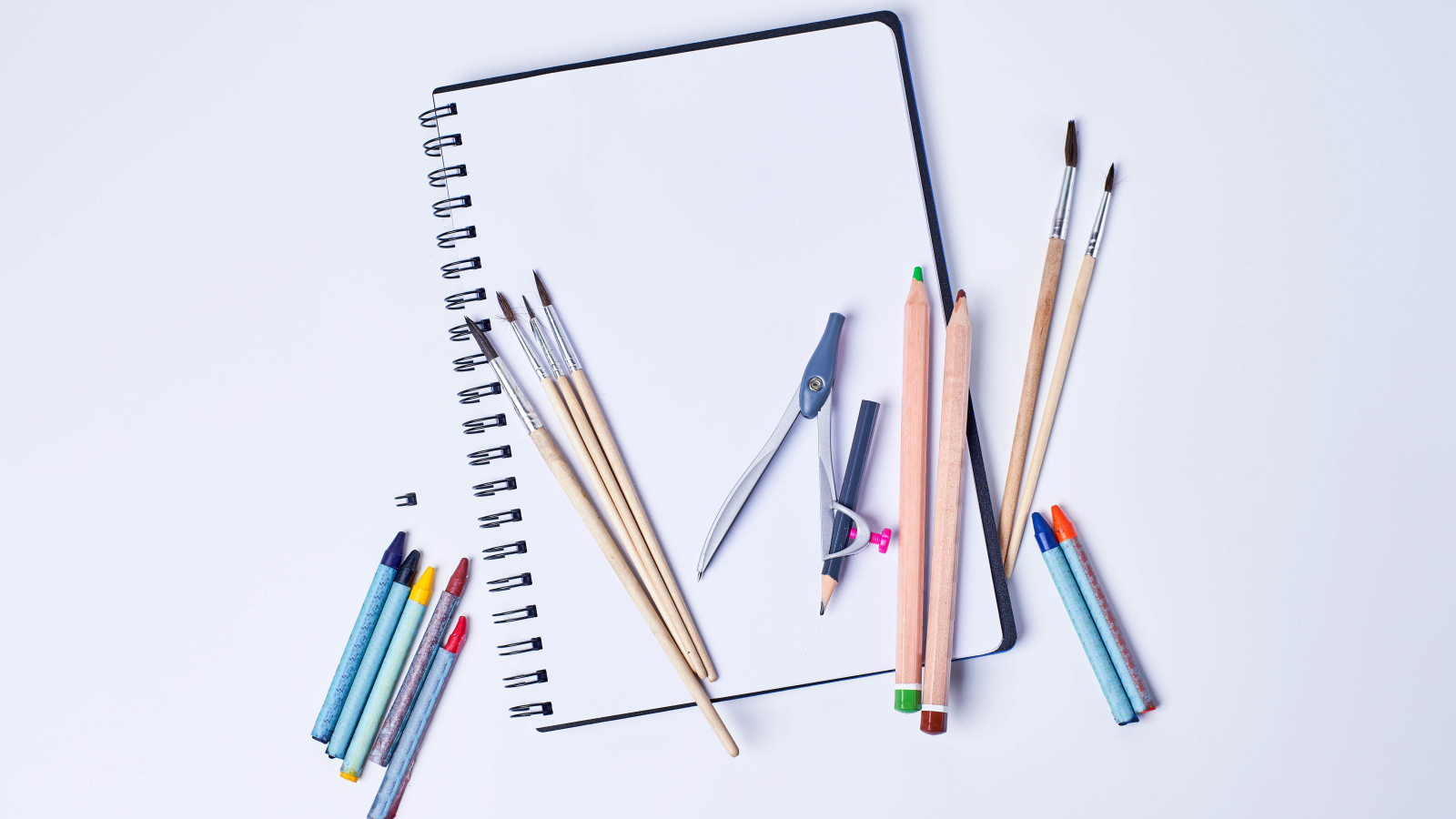 Карандаши, кисти и блокнот для рисования на сером фоне