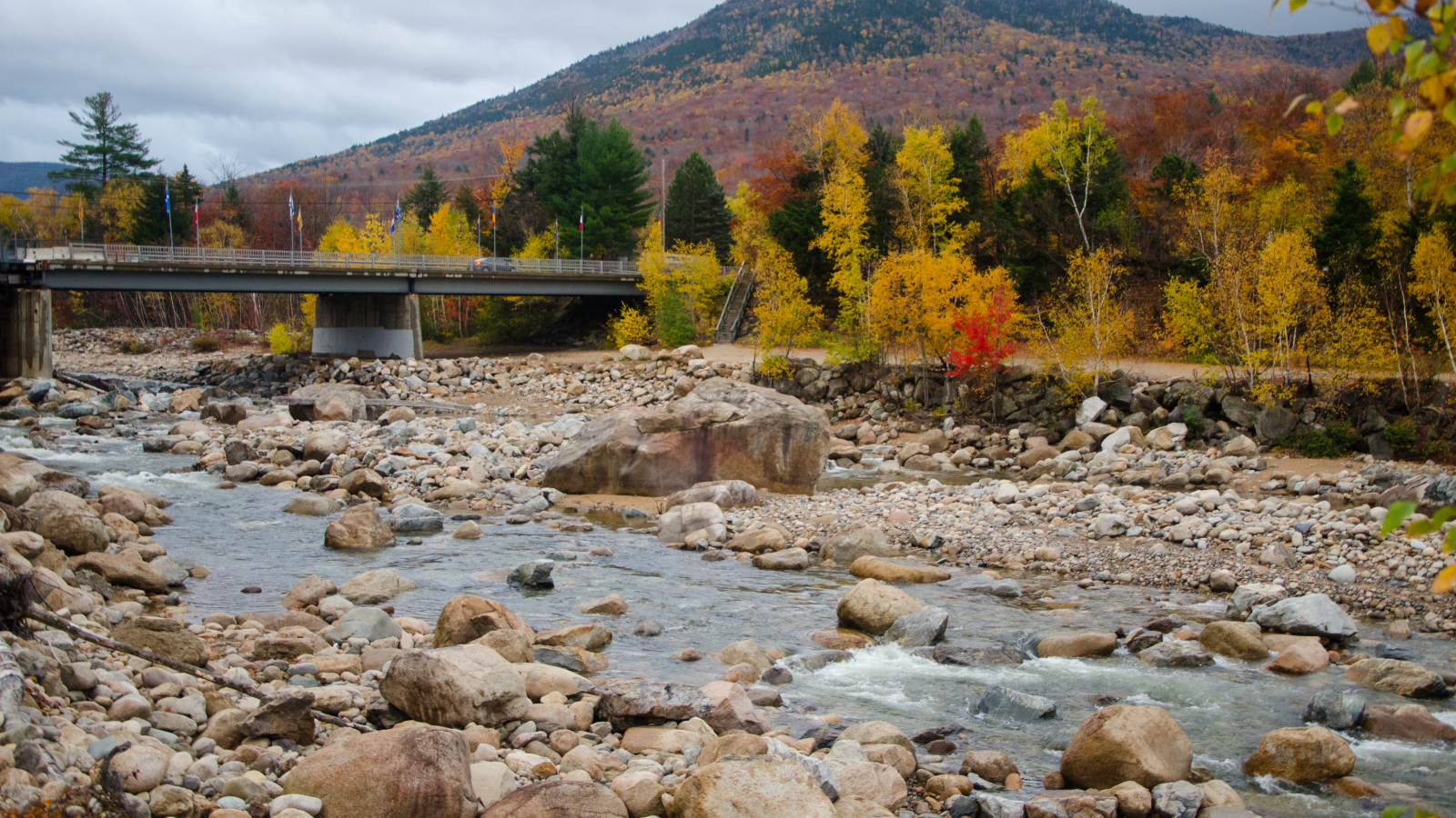 Камни в реке на фоне горы осенью