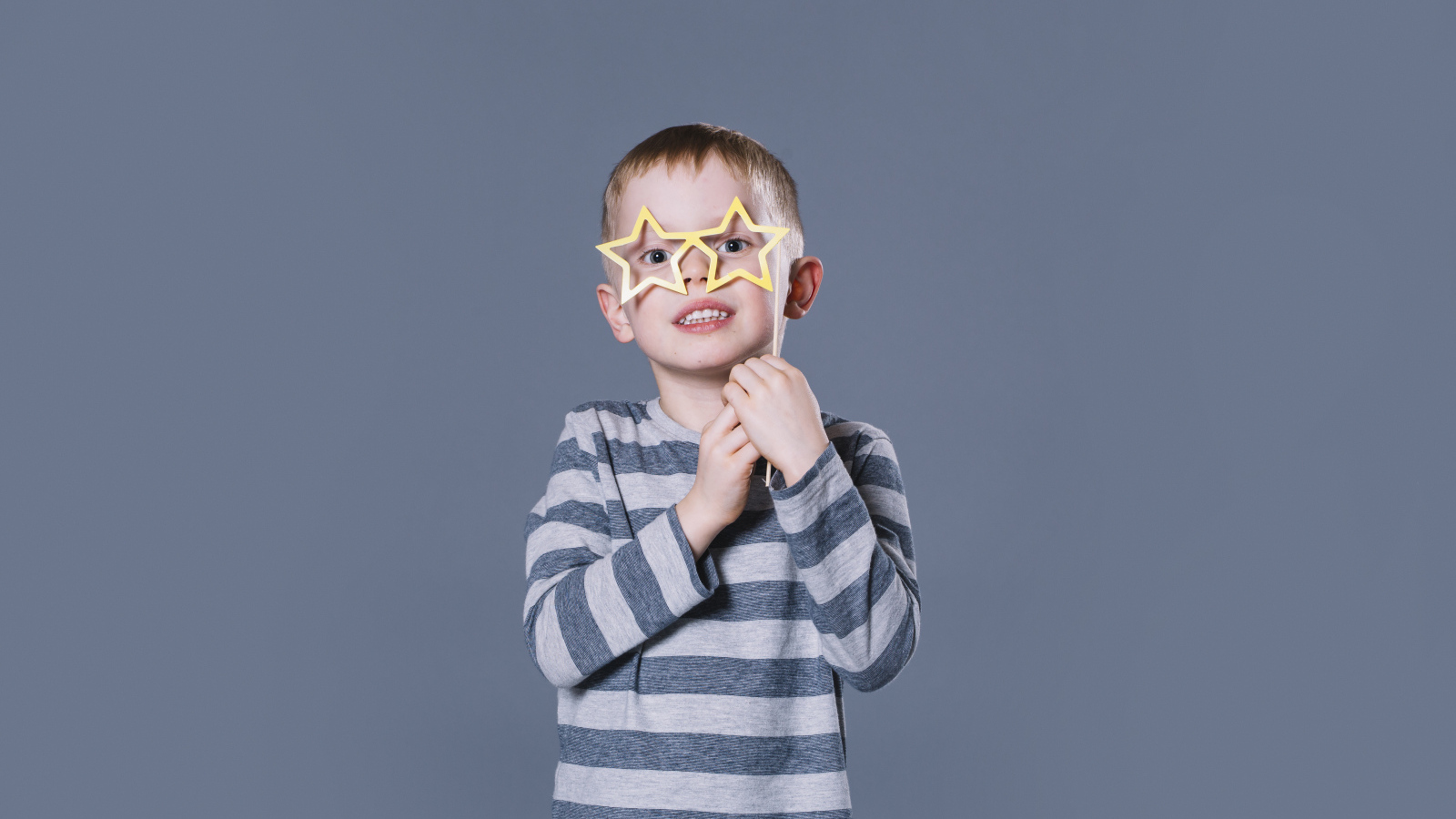 Маленький мальчик с очками в форме звезд на сером фоне