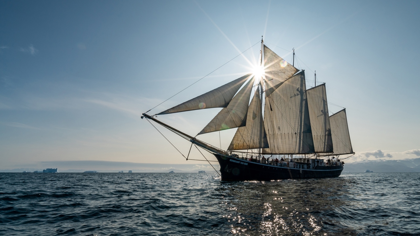 Корабль с белыми парусами в лучах солнца