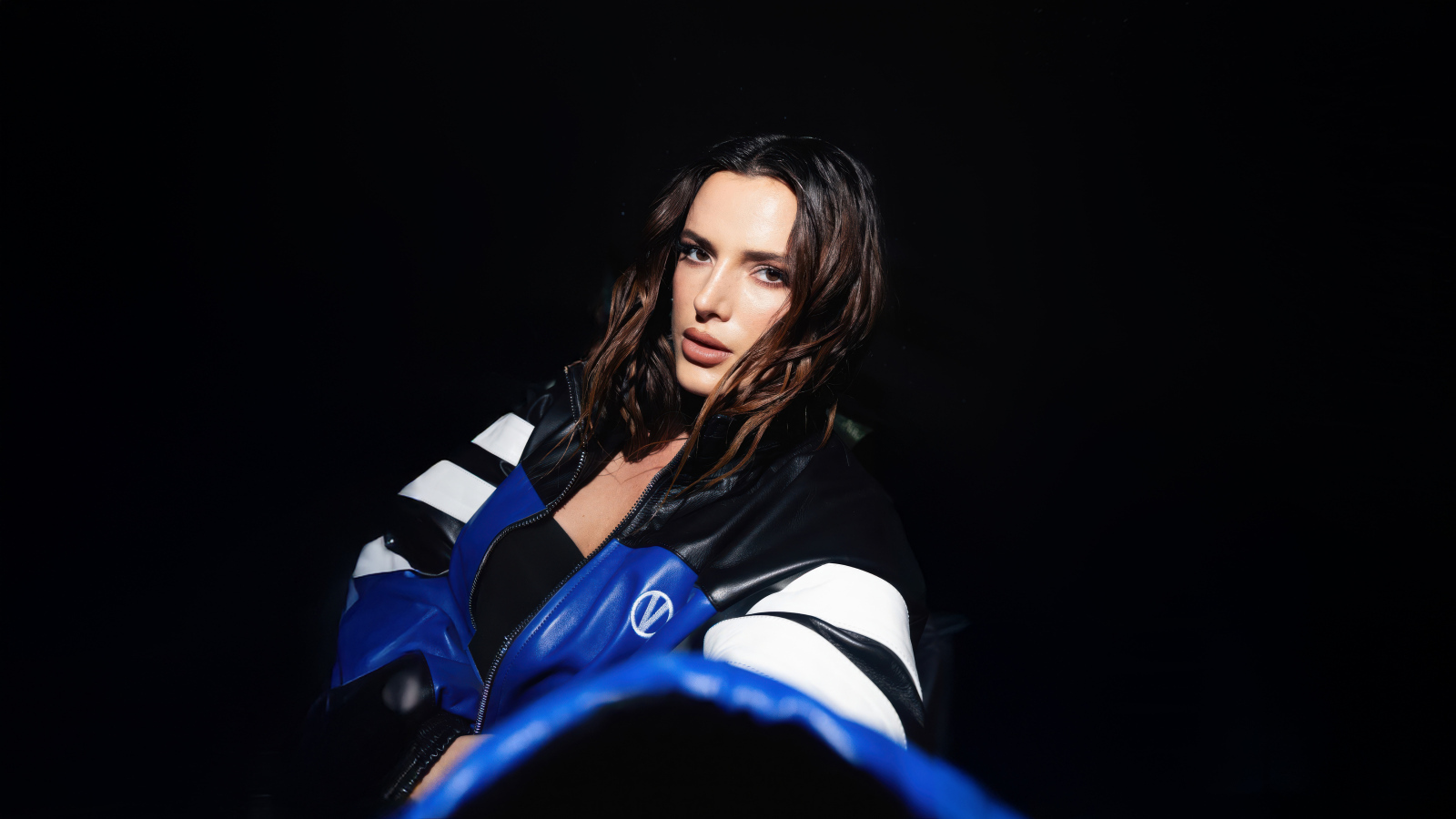 Актриса Белла Торн в кожаной куртке на черном фоне