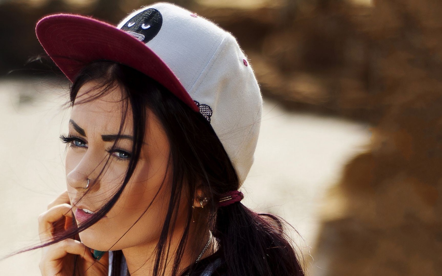 Девушка брюнетка в кепке и с пирсингом в носу