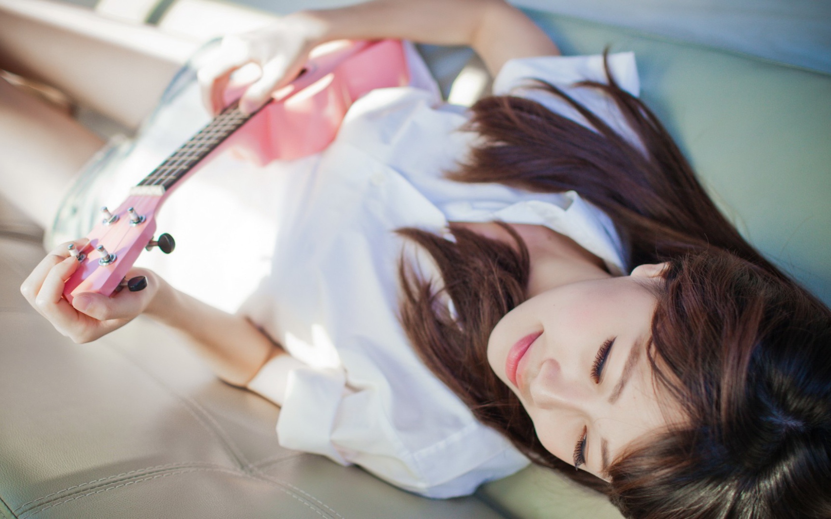 Брюнетка и розовая гитара на диване