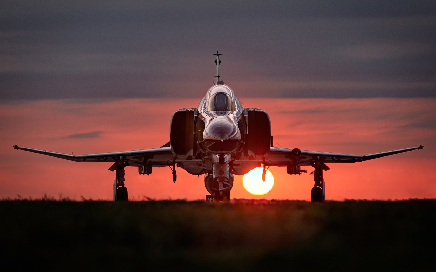 Истребитель F-4 Phantom II стоит на фоне заката