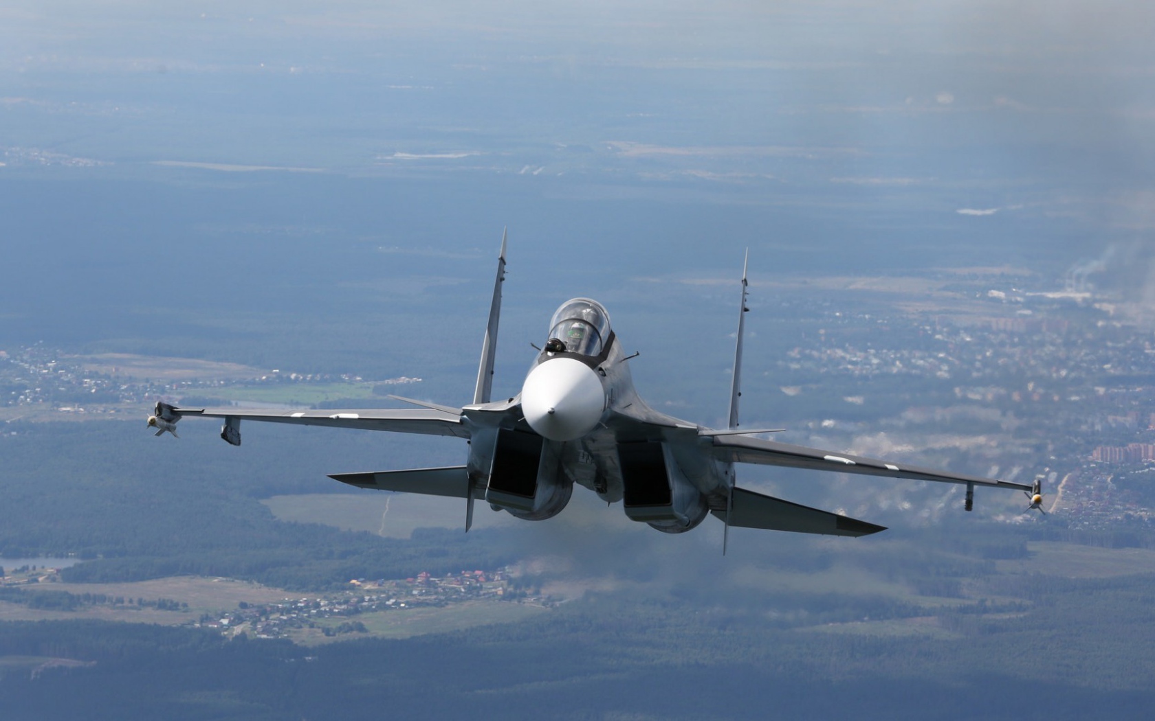 Самолет СУ-27 летит над городом