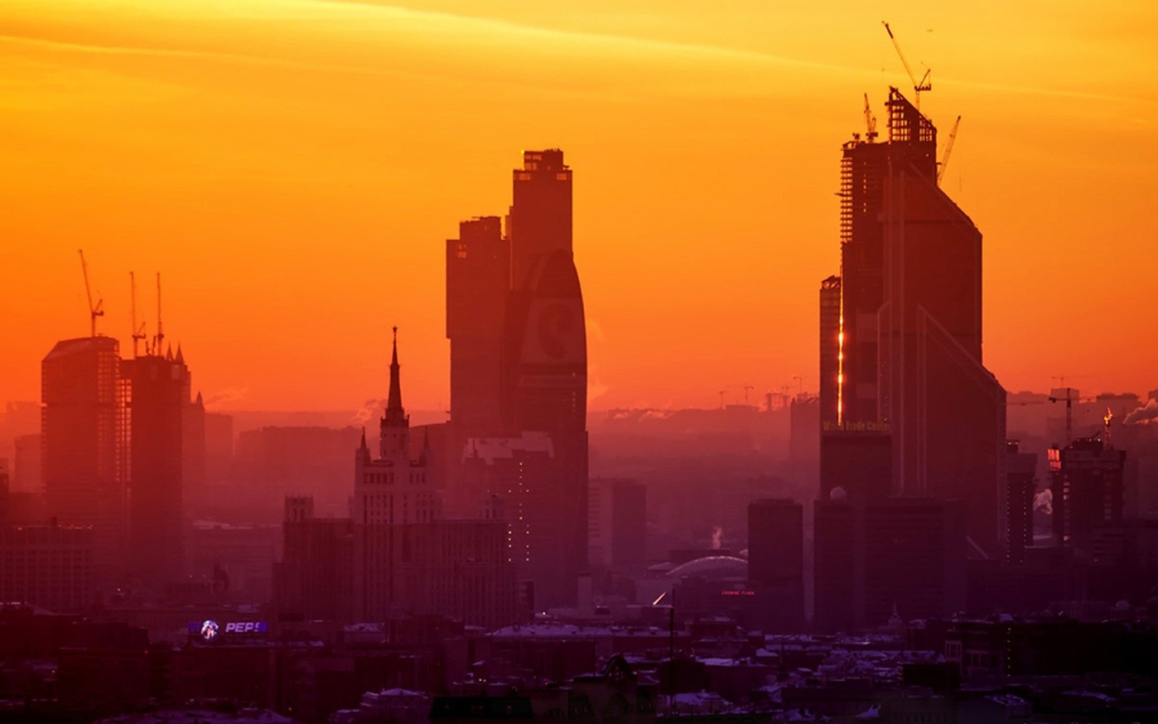 Стройка небоскребов на фоне оранжевого неба