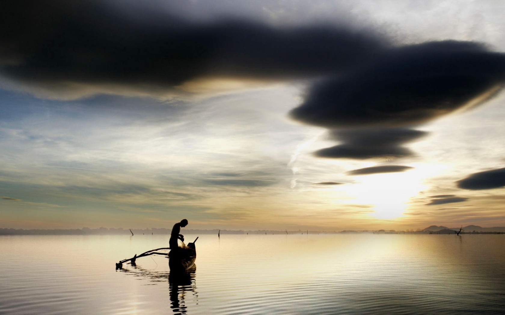 Рыбак достает улов из своей лодки