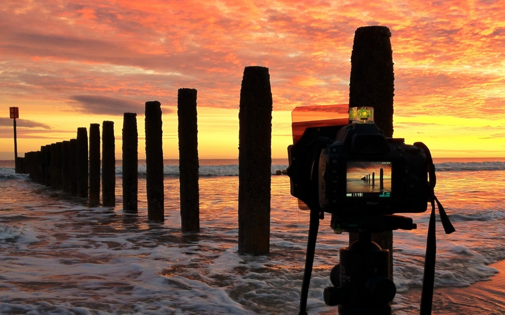 Фотограф снимает закат на берегу моря