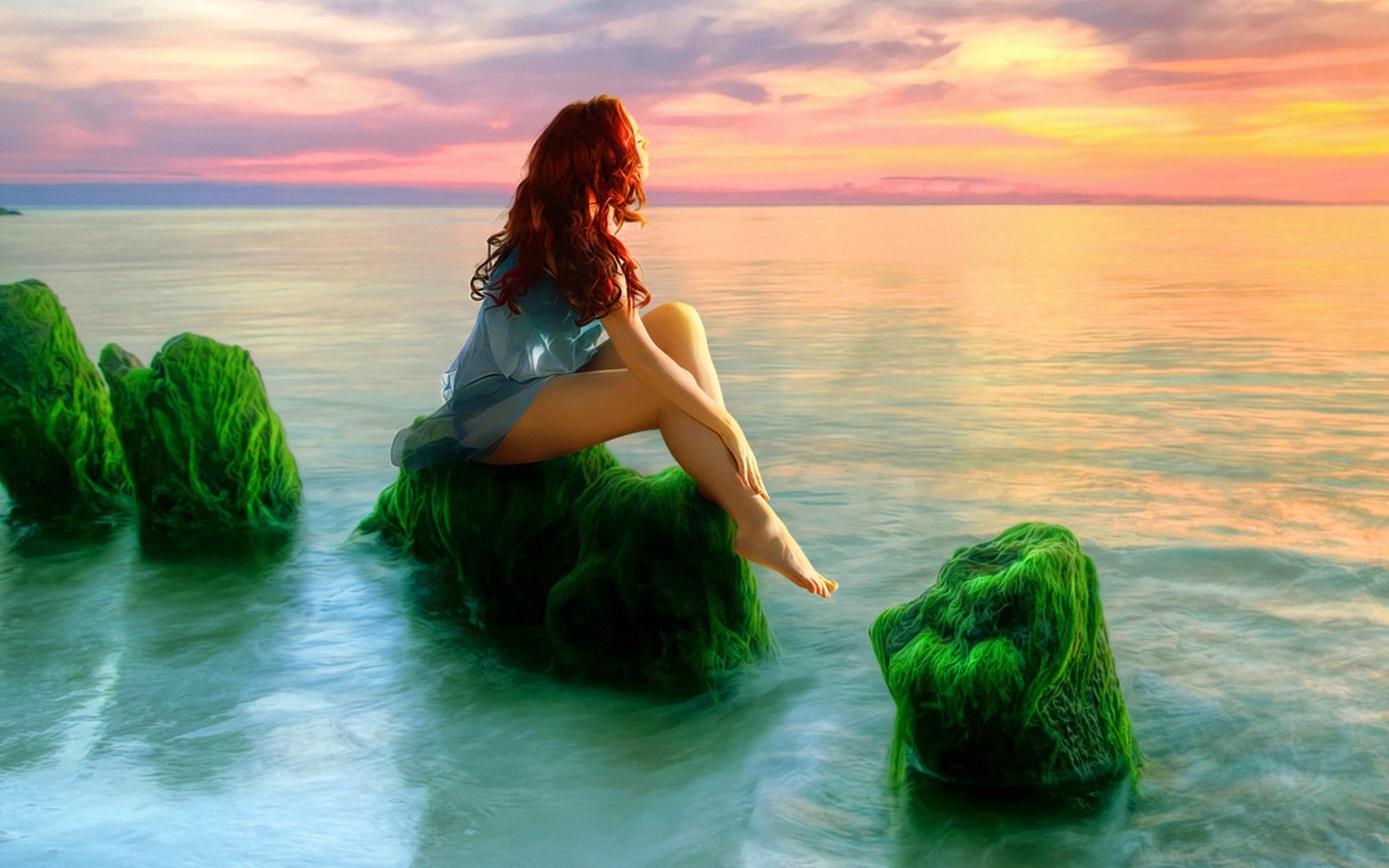 Русалка на зеленых камнях смотрит на закат