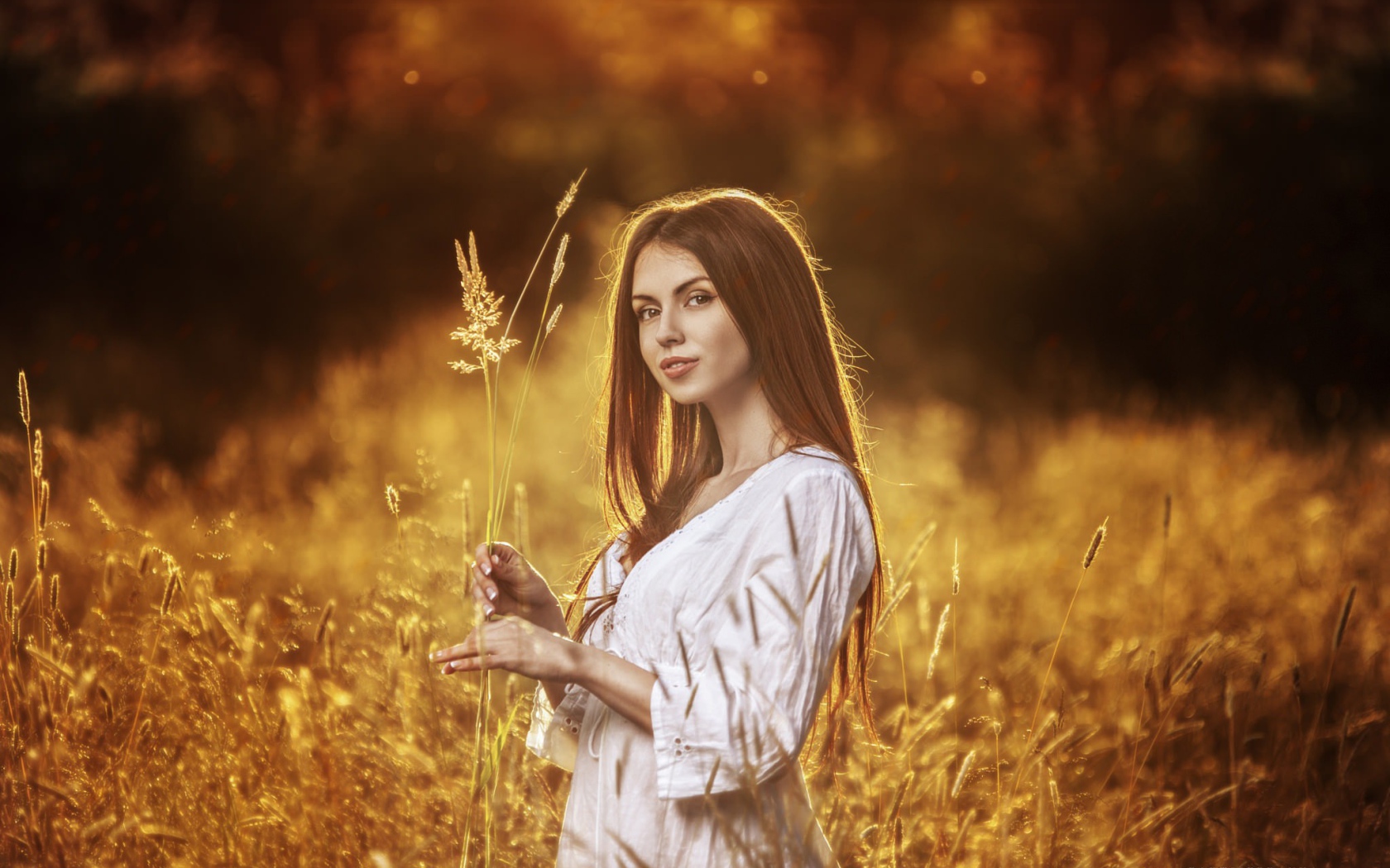 Девушка в белом платье держит в руке колоски