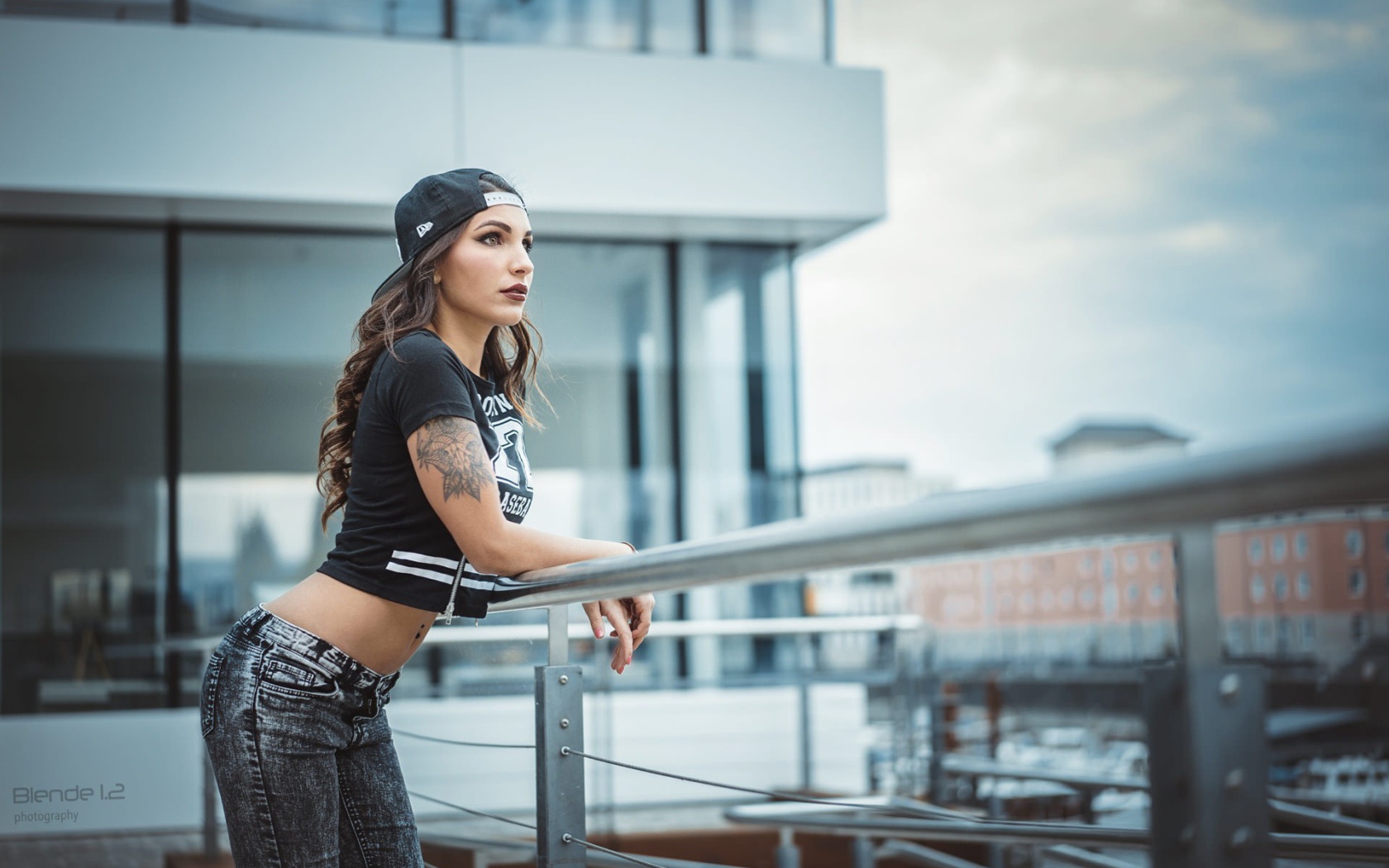 Девушка в кепке с тату смотрит на порт