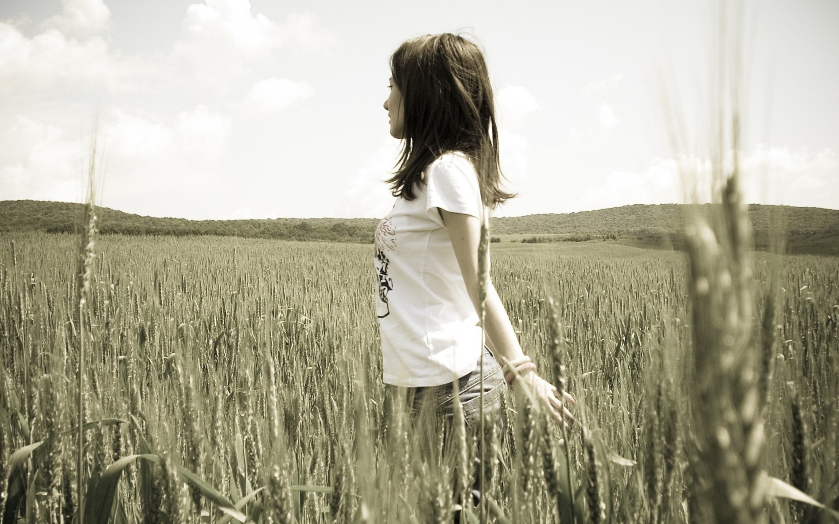 Девушка в белой футболке гуляет по пшеничному полю