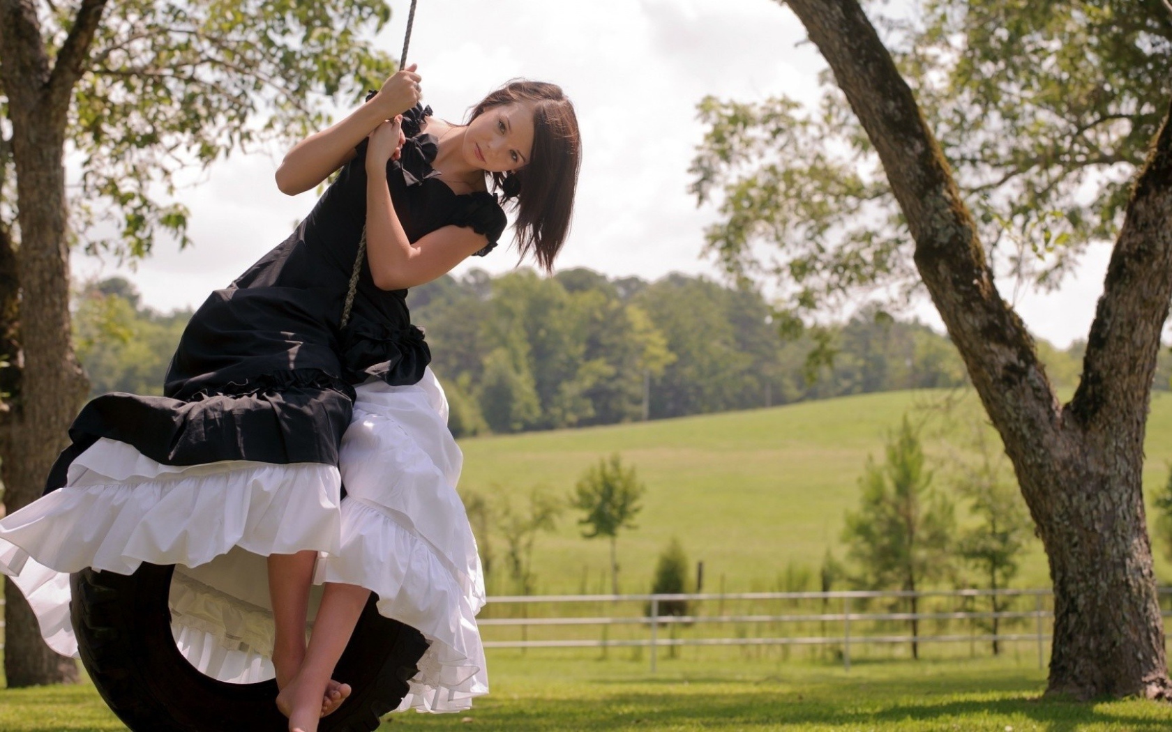 Девушка в черном платье на качелях