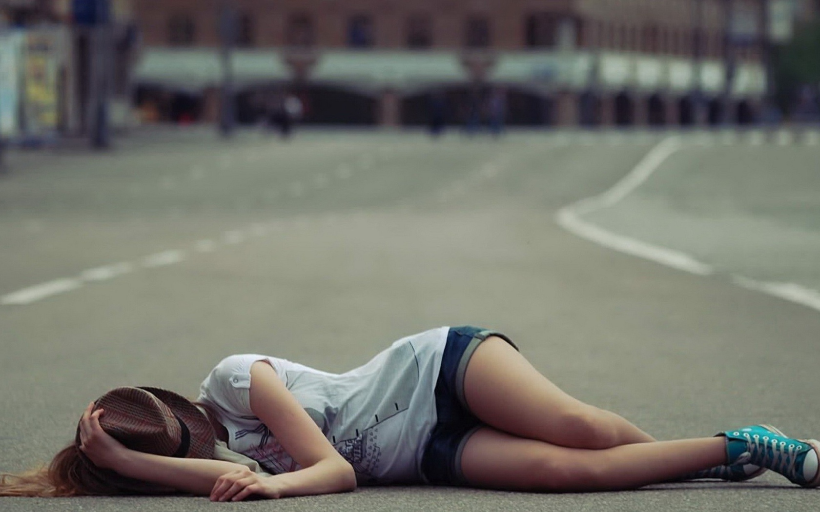 Девушка в шляпе лежит на дороге