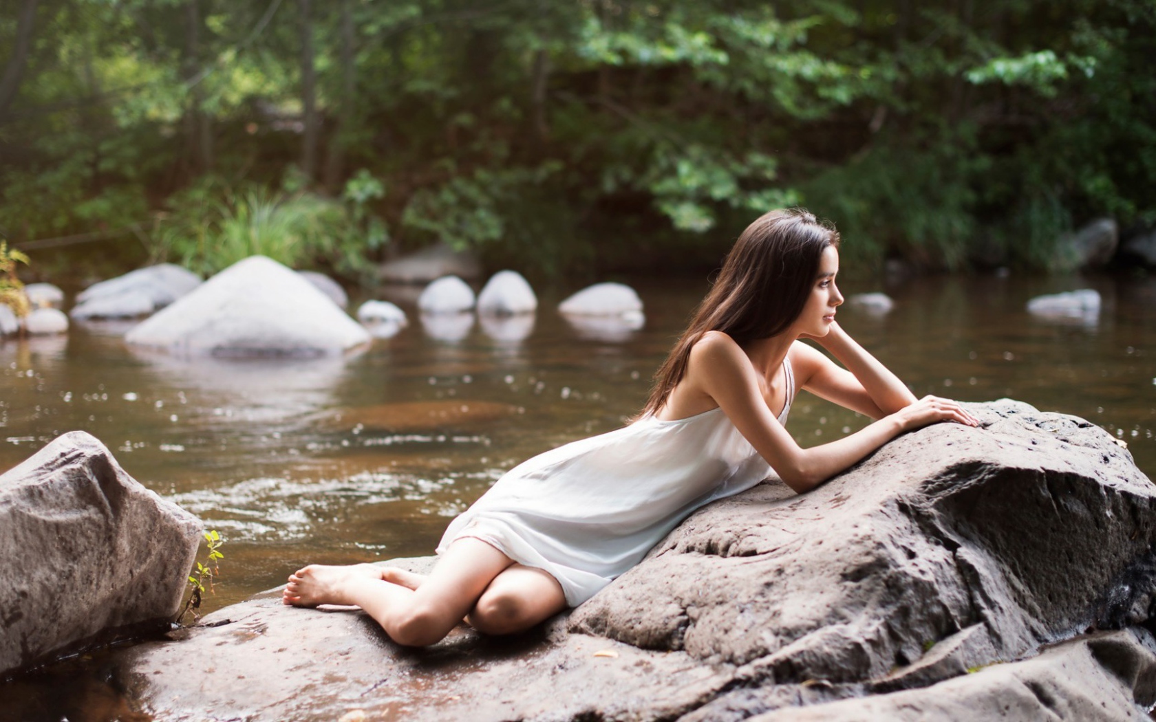 Девушка лежит на камне у реки