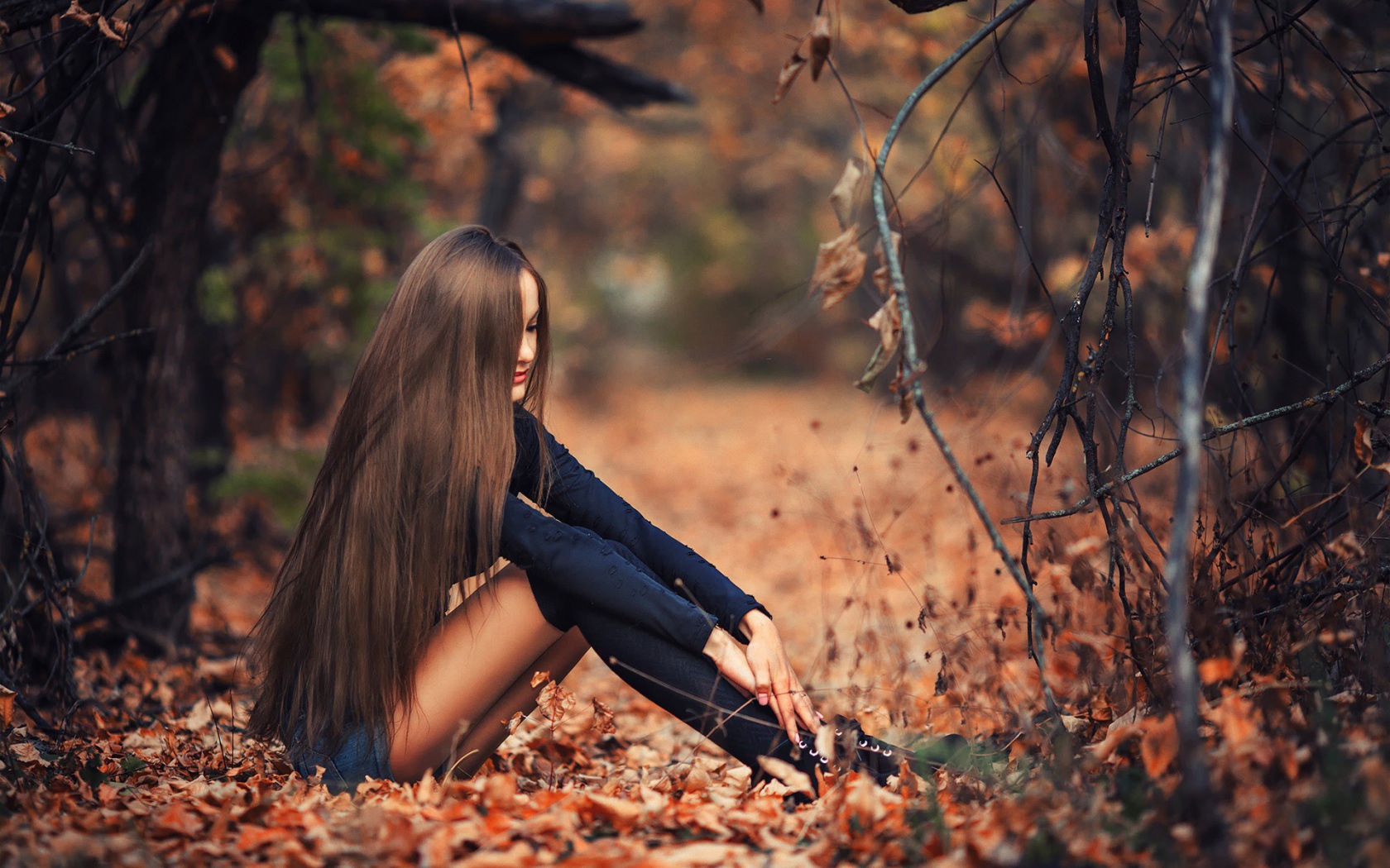 Девушка сидит на осенней листве