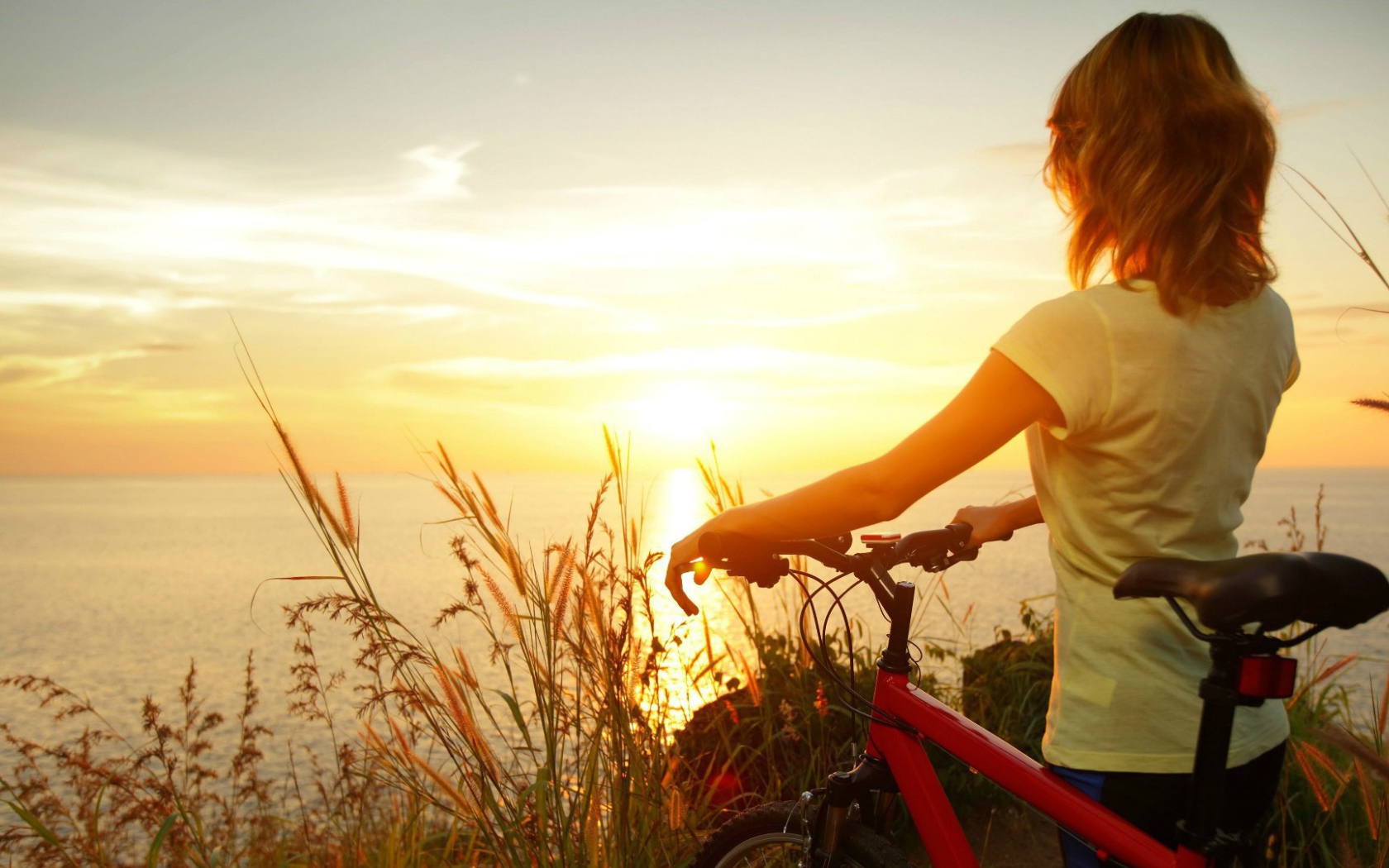 Девушка с велосипедом смотрит на закат