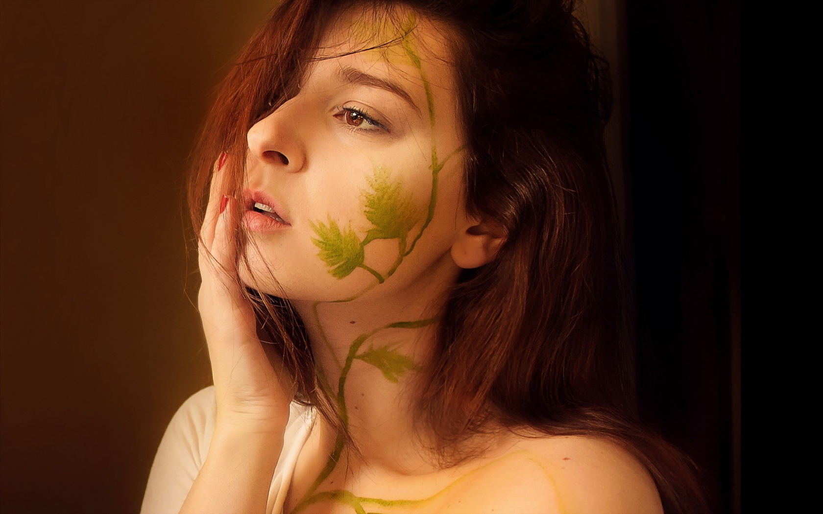 Рисунок зеленых листьев на лице и шее девушки