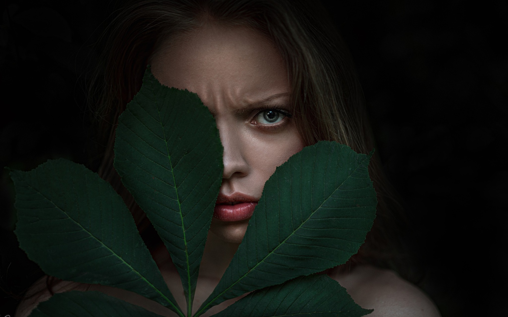 Девушка прикрыла лицо листьями каштана