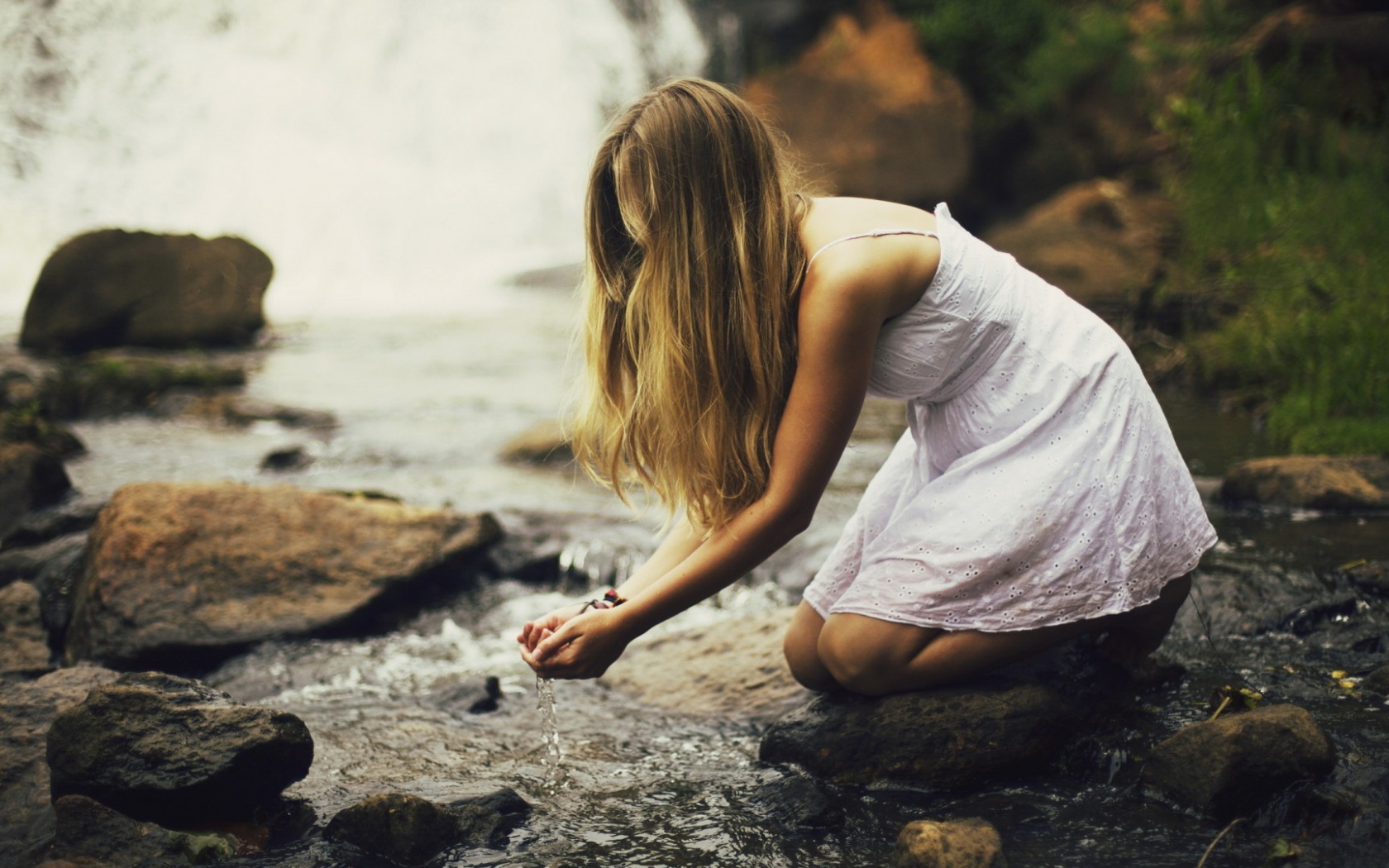 Девушка черпает воду из ручья