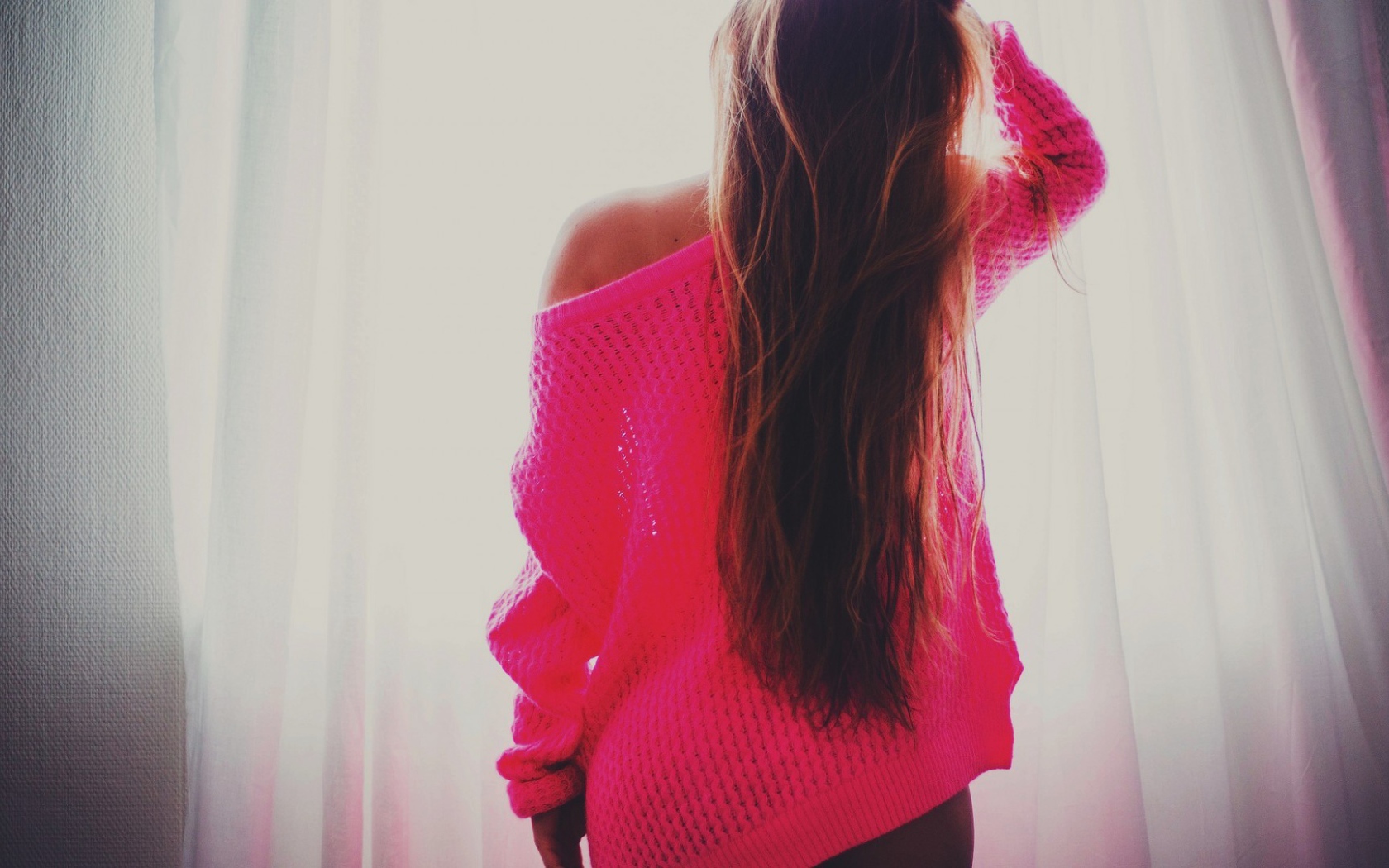 Девушка в розовой кофте стоит спиной
