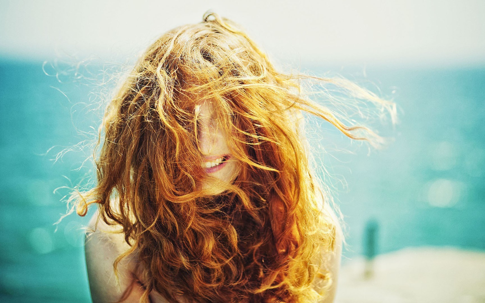 Ветер растрепал рыжие волосы у девушки