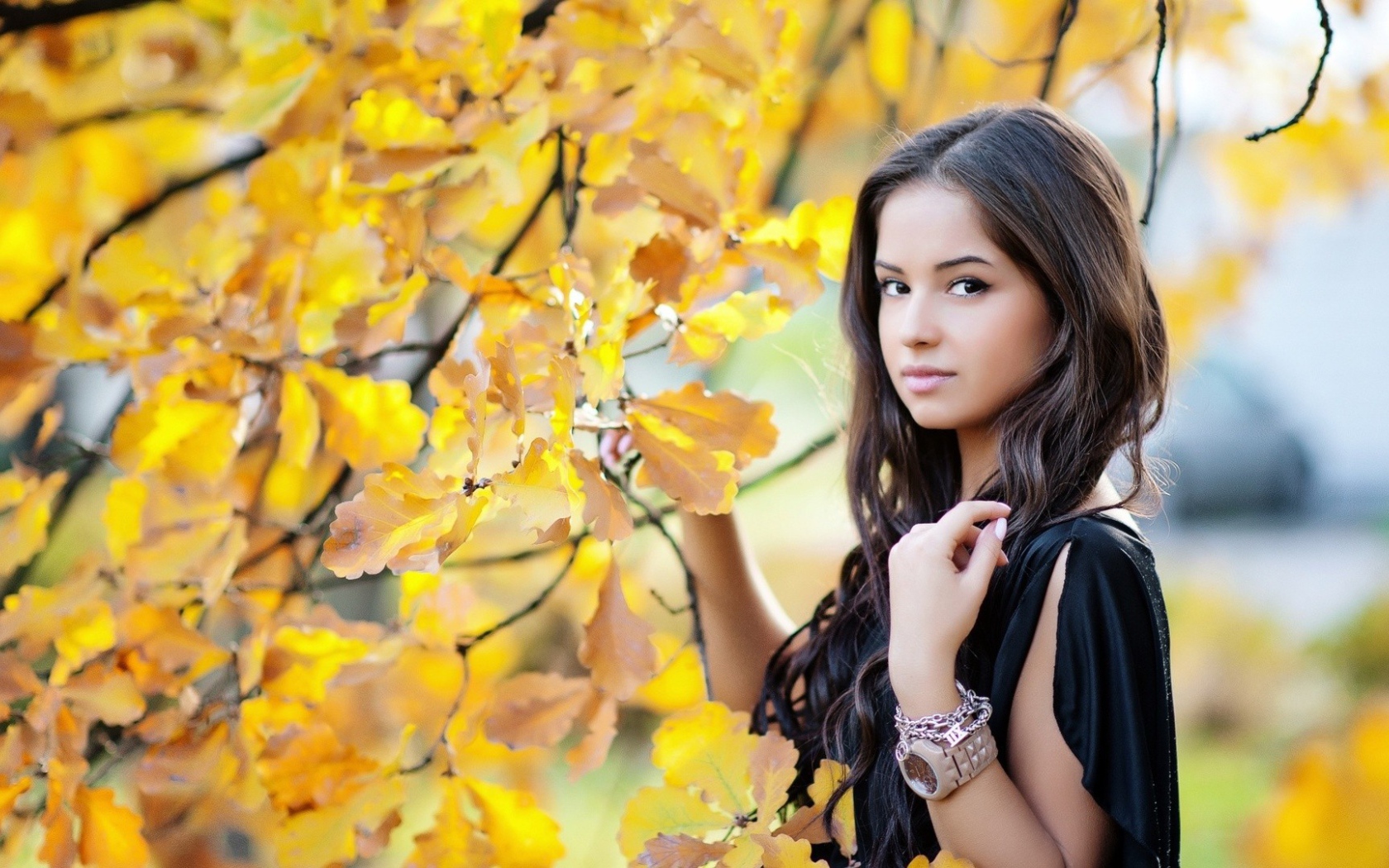 Молодая брюнетка у осеннего дерева