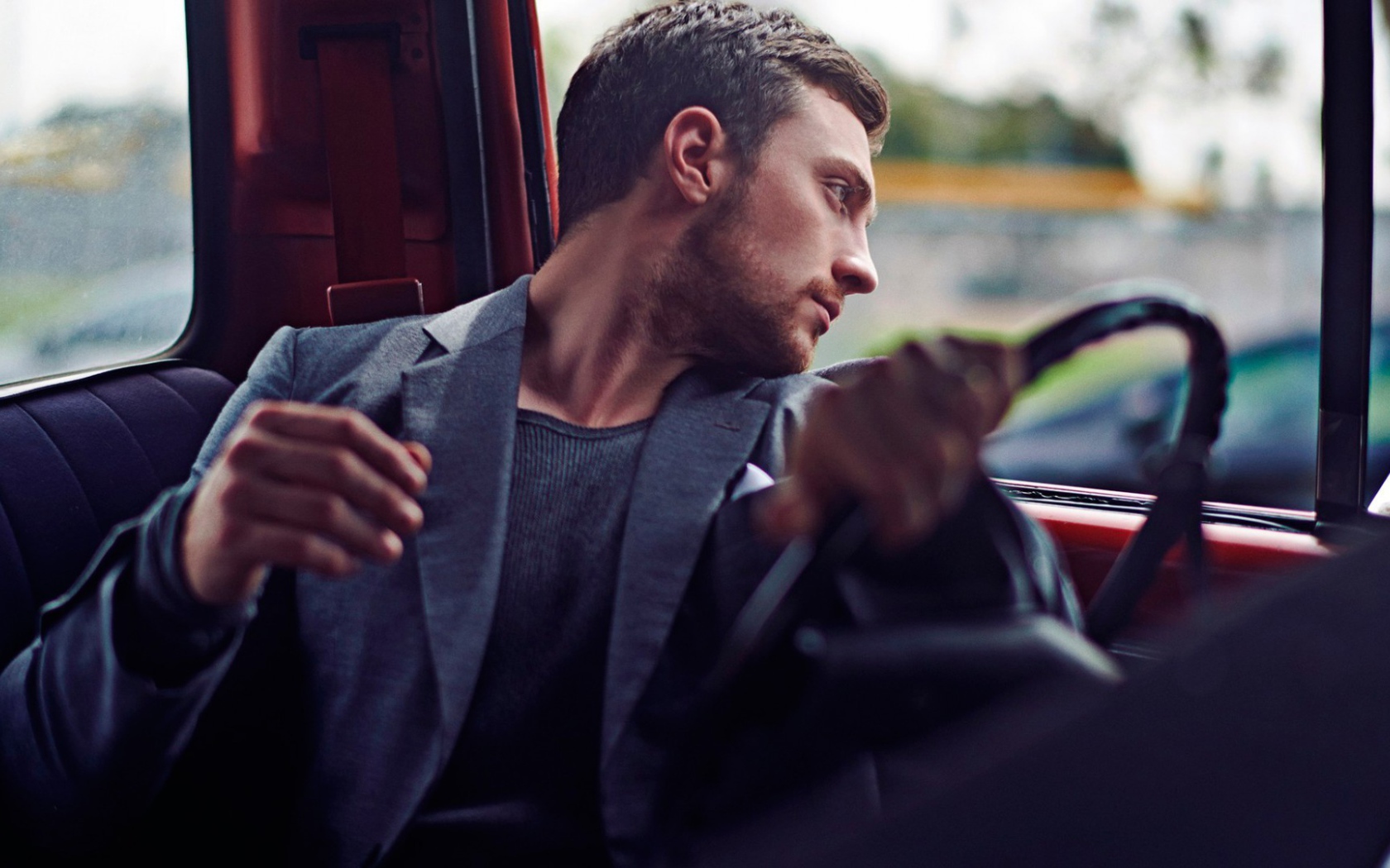 Мужчина за рулем смотрит в окно автомобиля