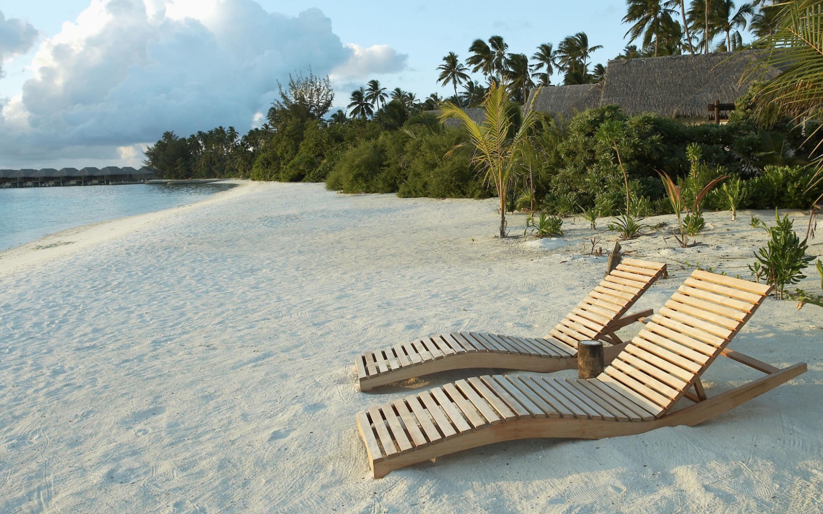 Деревянные шезлонги на белом песке пляжа