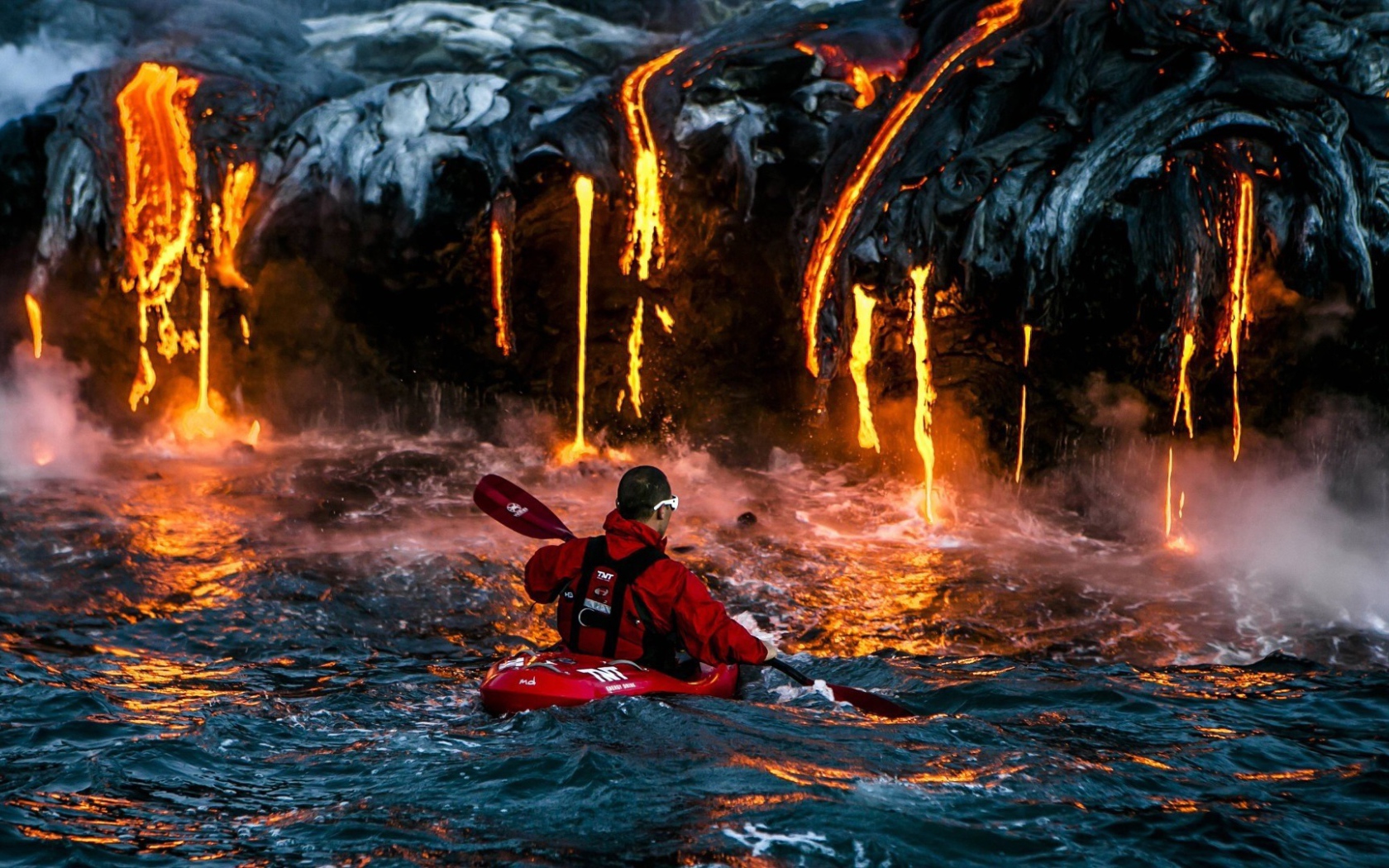 Человек на фоне лавы, стекающей в море