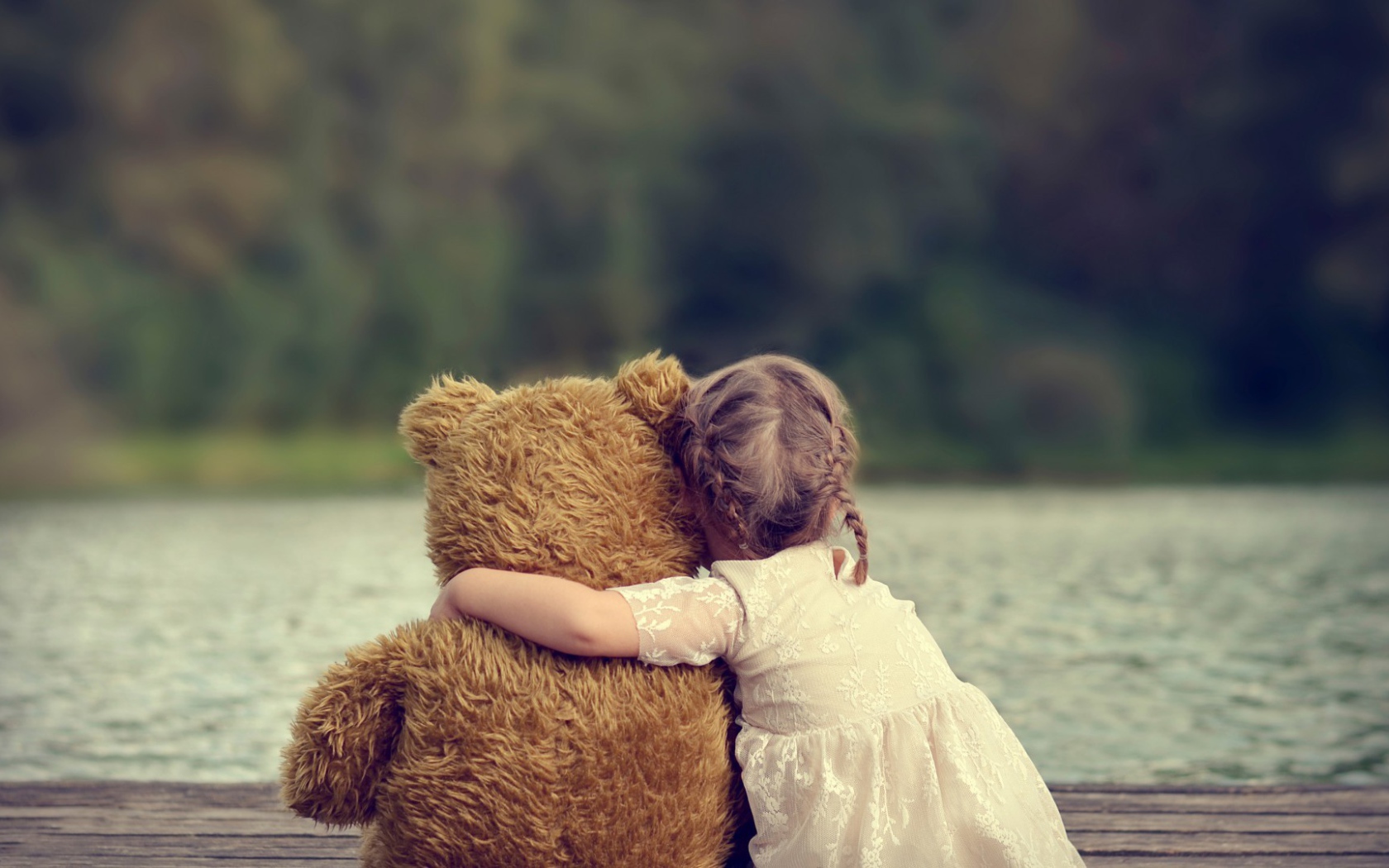 Девочка сидит в обнимку с плюшевым медведем