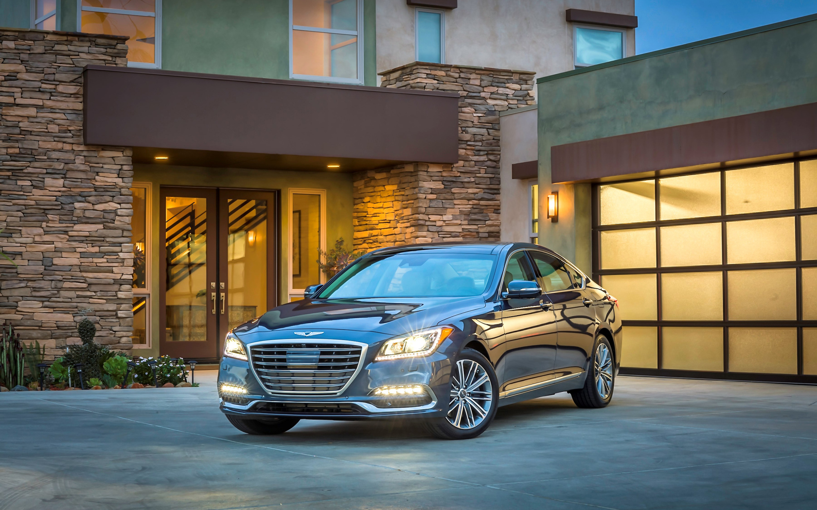 Серебристый автомобиль Genesis G80 с включенными фарами