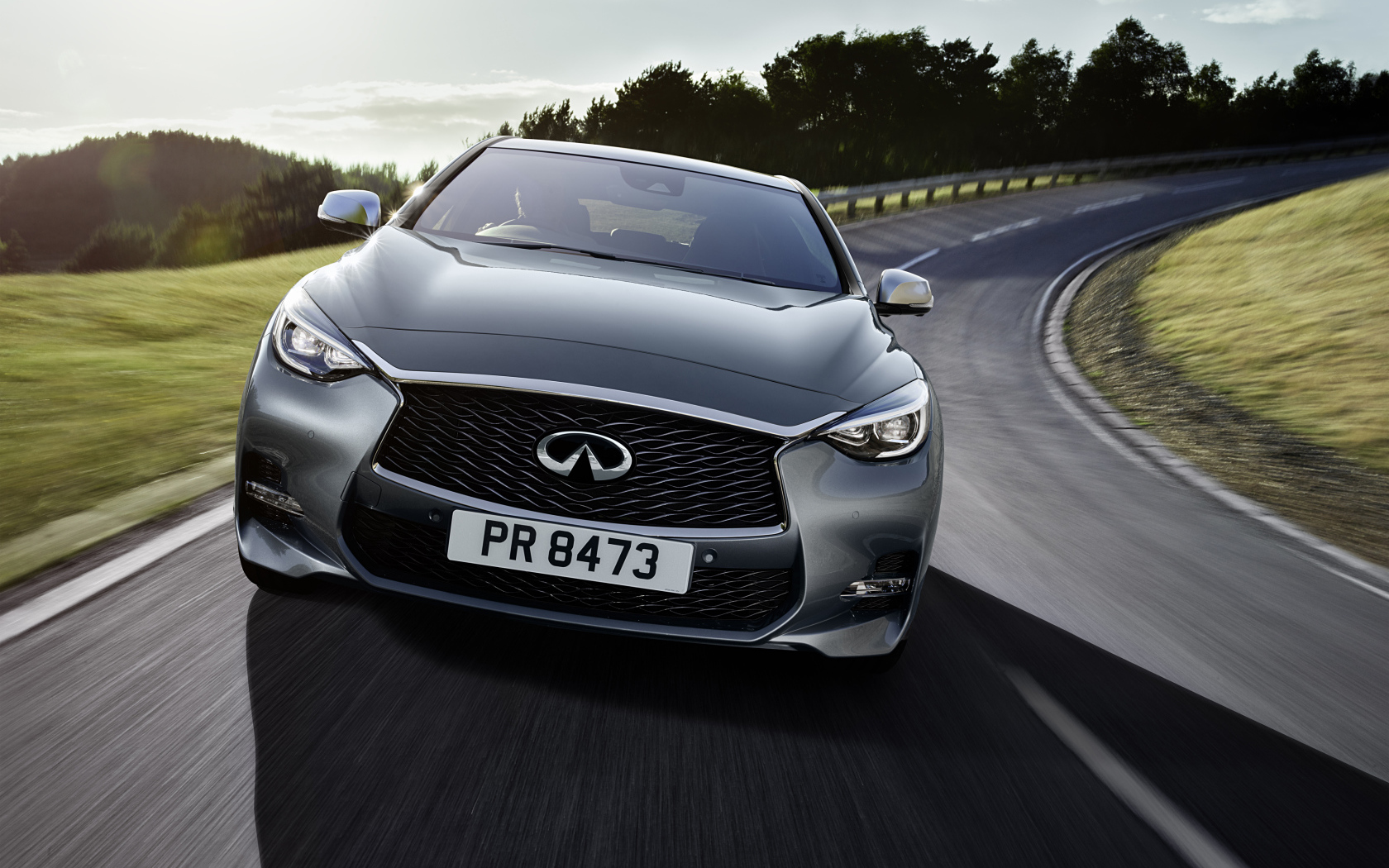 Серебристый автомобиль Infiniti Q30 на трассе