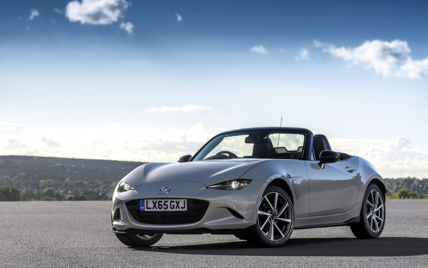 Серебристый кабриолет Mazda MX-5 на фоне красивого неба