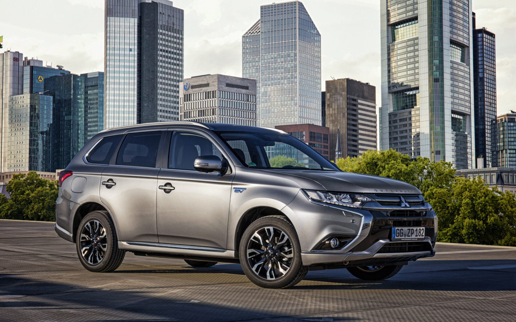 Серебристый автомобиль Mitsubishi Outlander на фоне небоскребов 