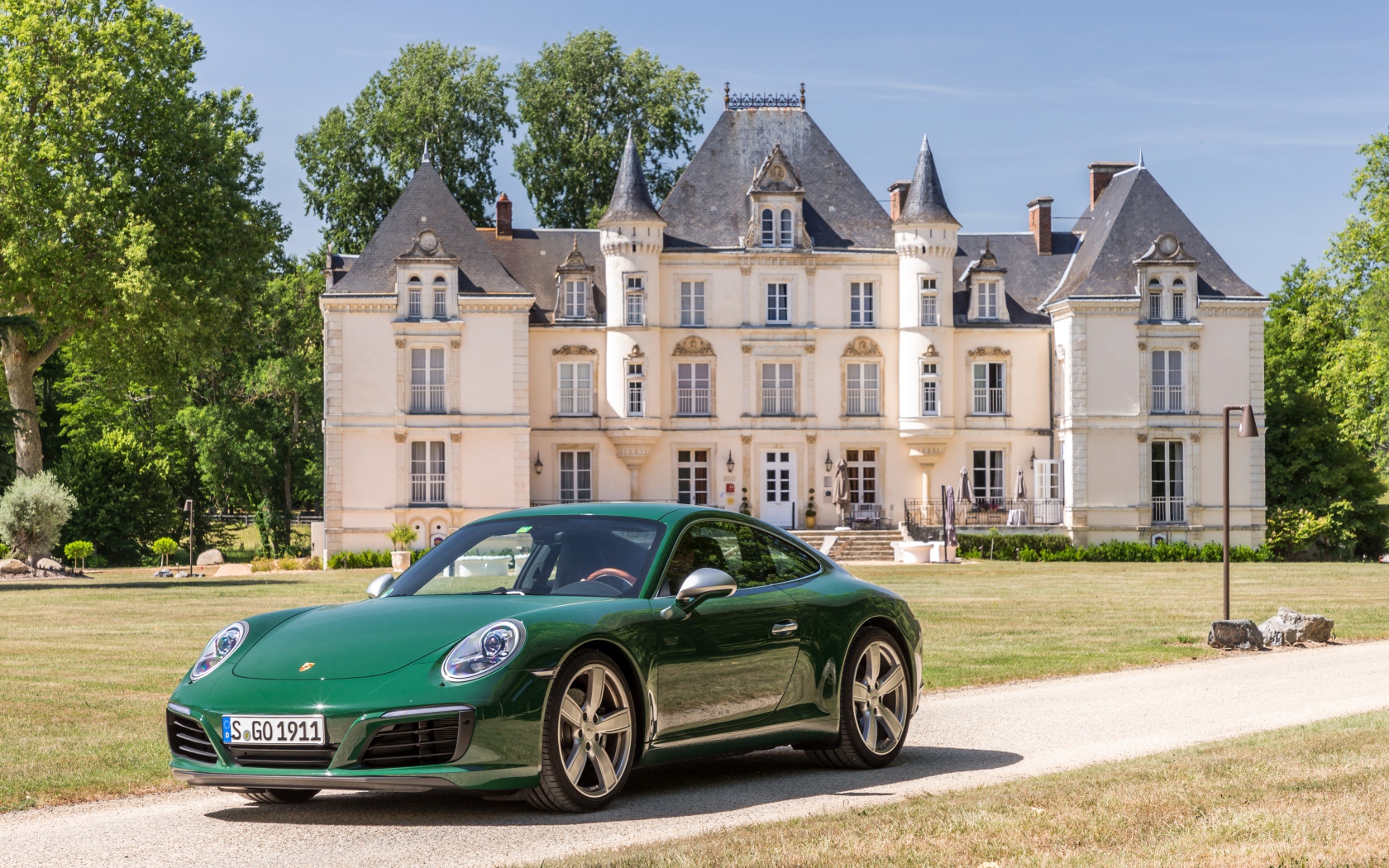 Зеленый спортивный автомобиль Porsche 911 Carrera на фоне дома