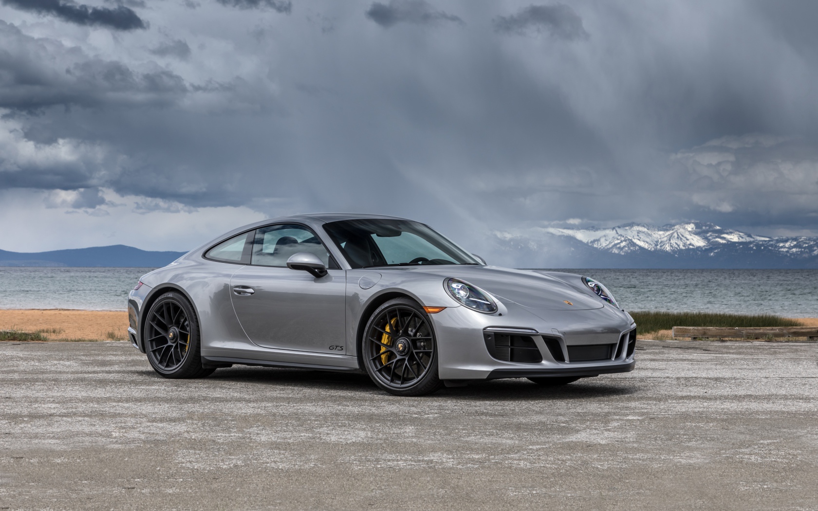 Серебристый автомобиль Porsche 911 Carrera 4 GTS Coupe на фоне грозового неба