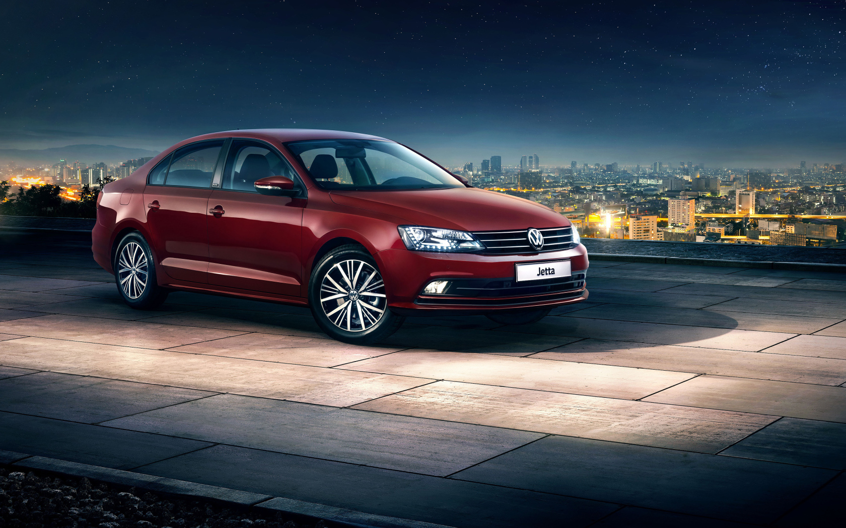 Красный автомобиль Volkswagen Jetta на фоне ночного города