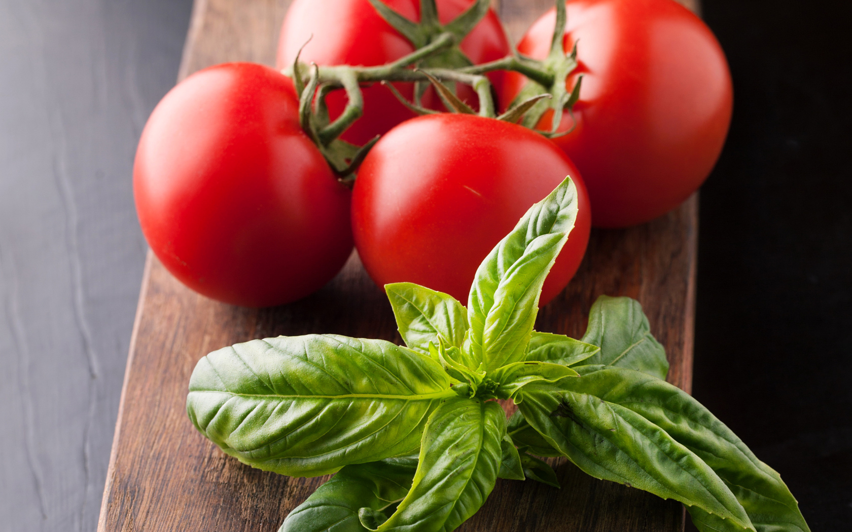 Свежие помидоры на разделочной с зеленью