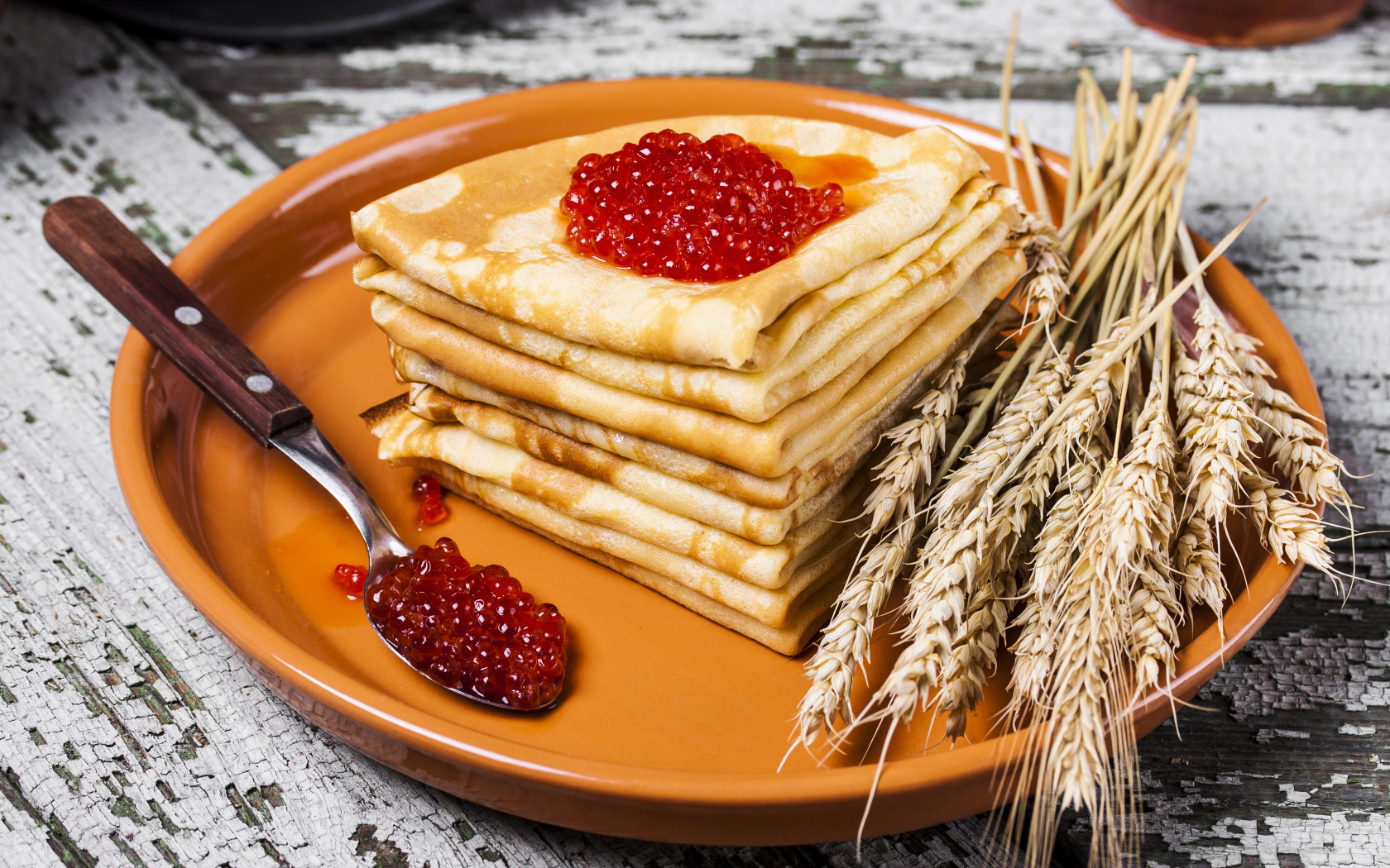 Блины с красной икрой и колосками пшеницы на тарелке